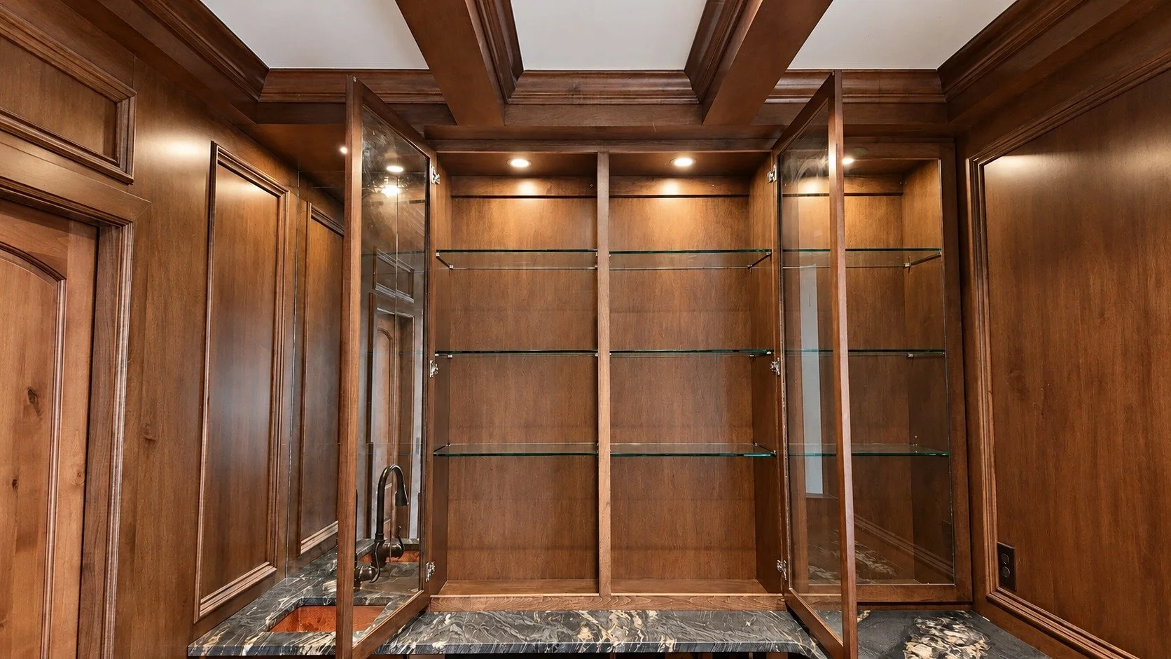 The bourbon room — illuminated glass shelving and richly detailed woodwork.