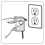 A hand plugging in an electrical cord to a wall outlet.