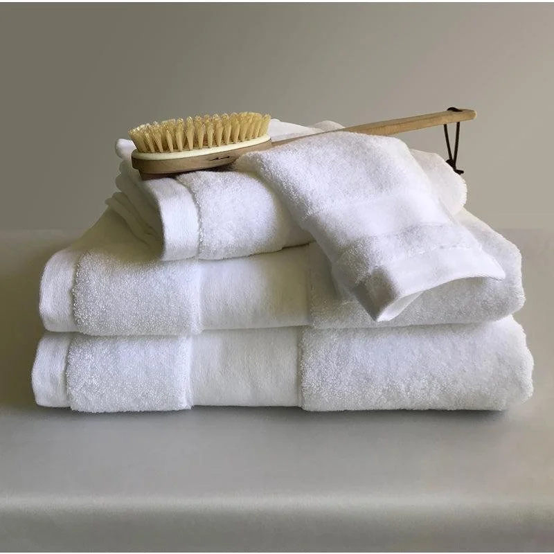 Stacked clean white towels with a wooden bath brush resting on top.