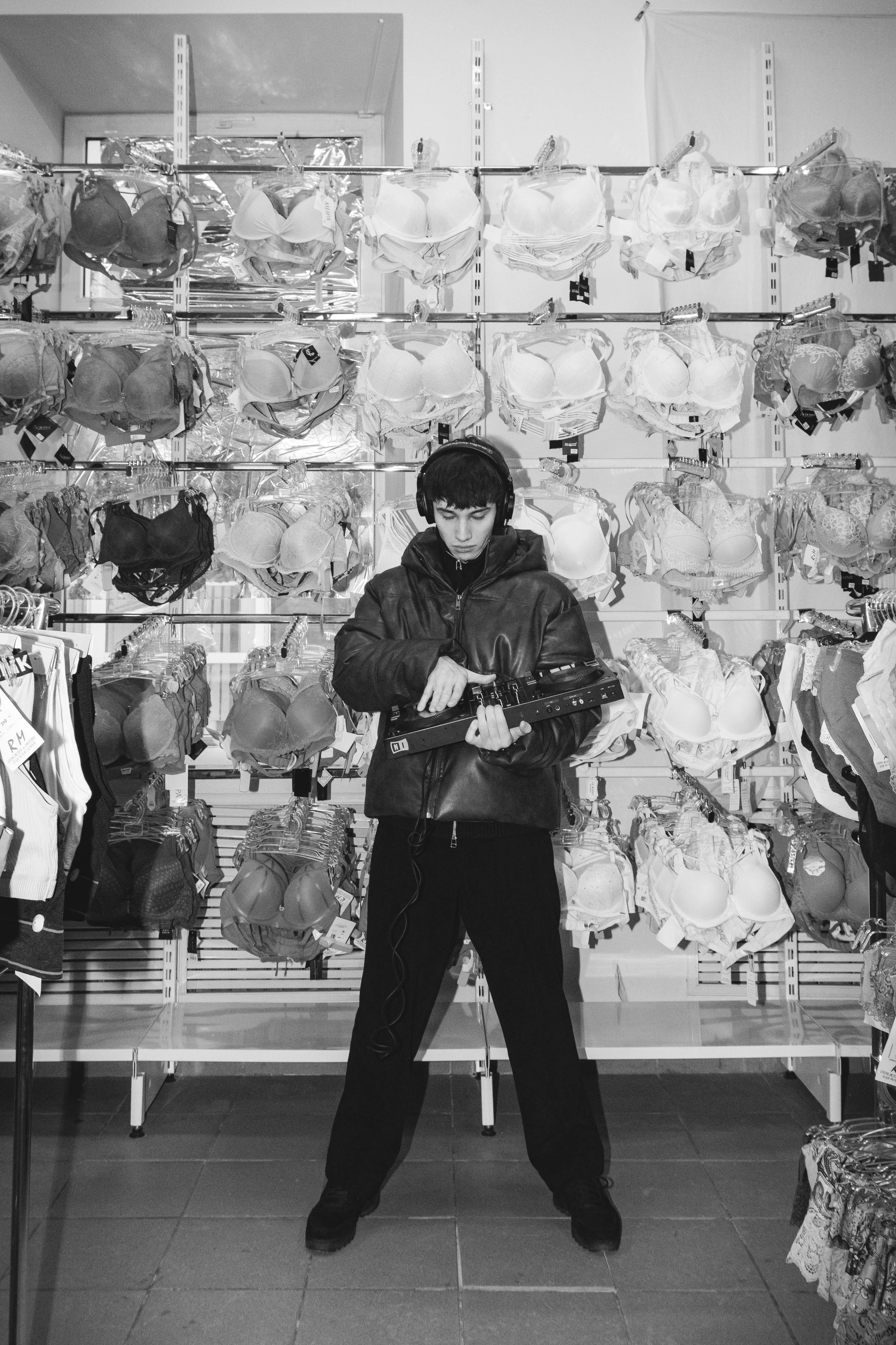 Person wearing headphones playing electronic instrument in front of bra display in a store