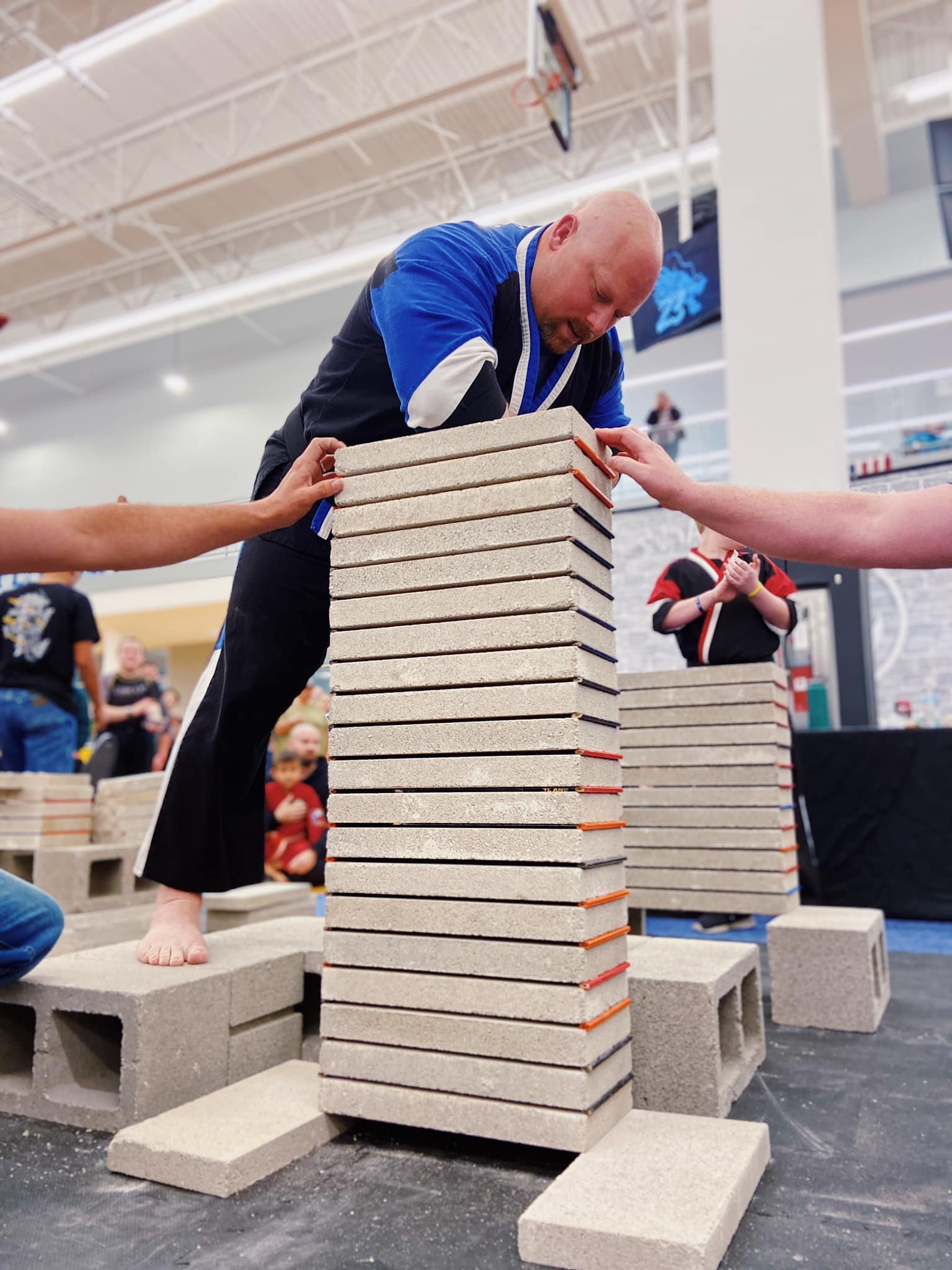 Person breaking concrete slabs with elbow at martial arts event