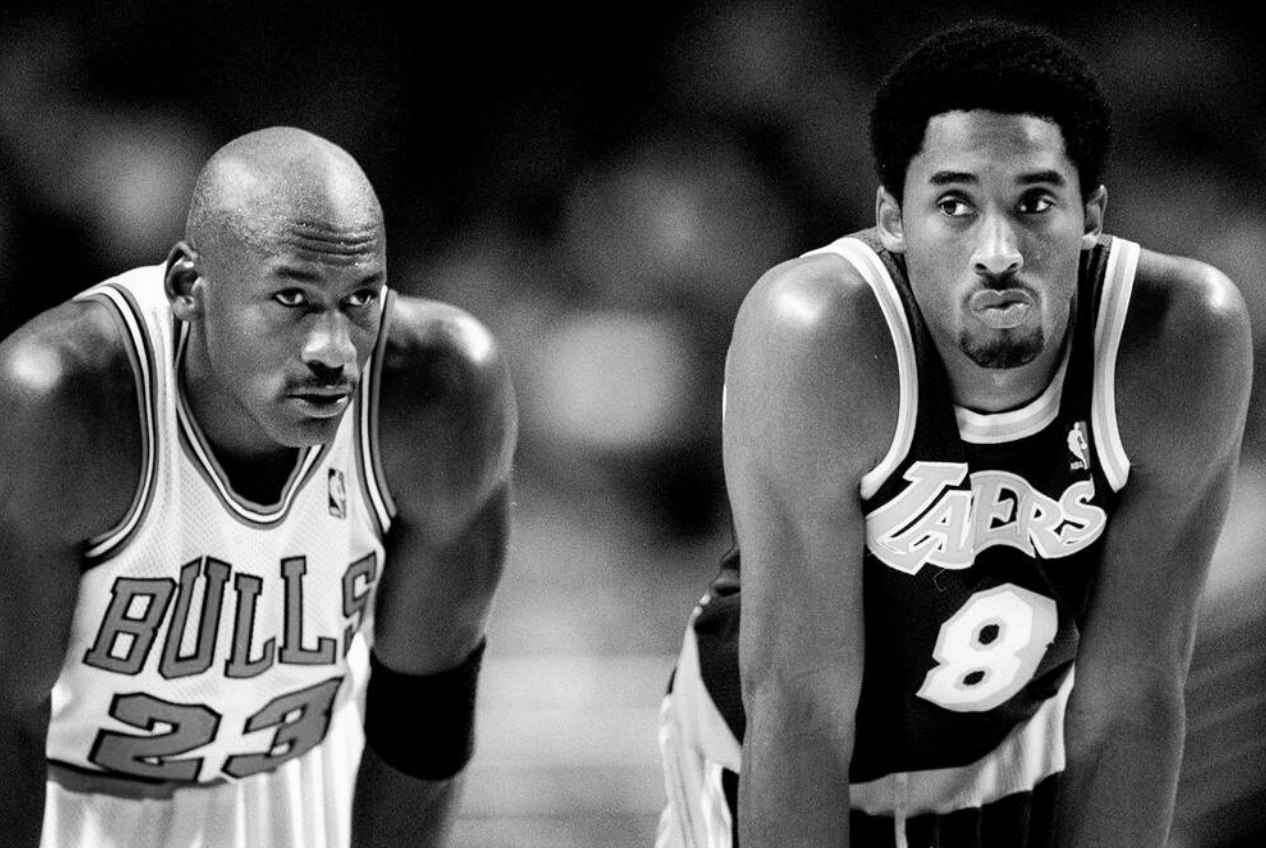 Two male basketball players, one from the Chicago Bulls and one from the Los Angeles Lakers, leaning forward during a game in black and white.