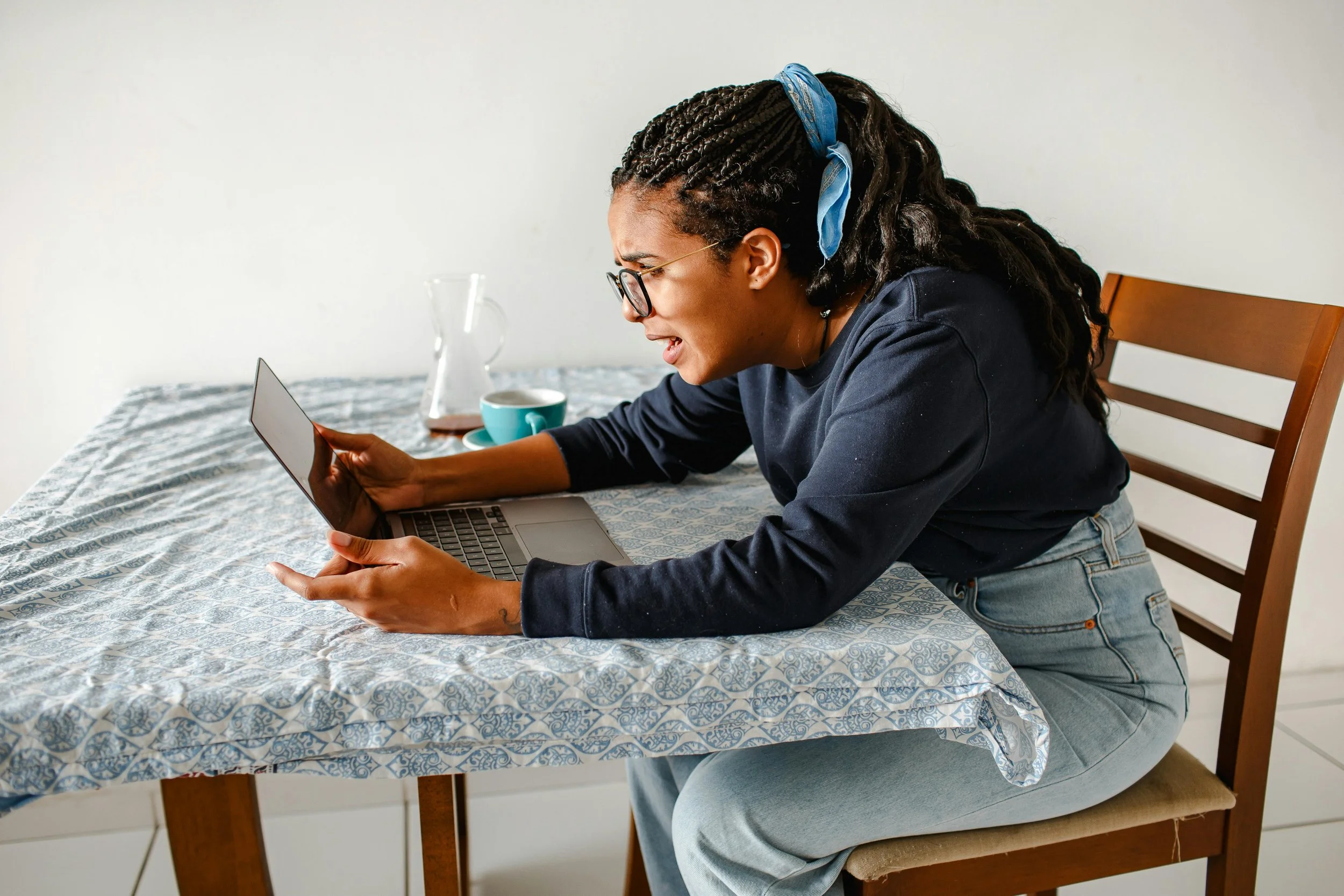 young female wearing glasses looking at a laptop screen