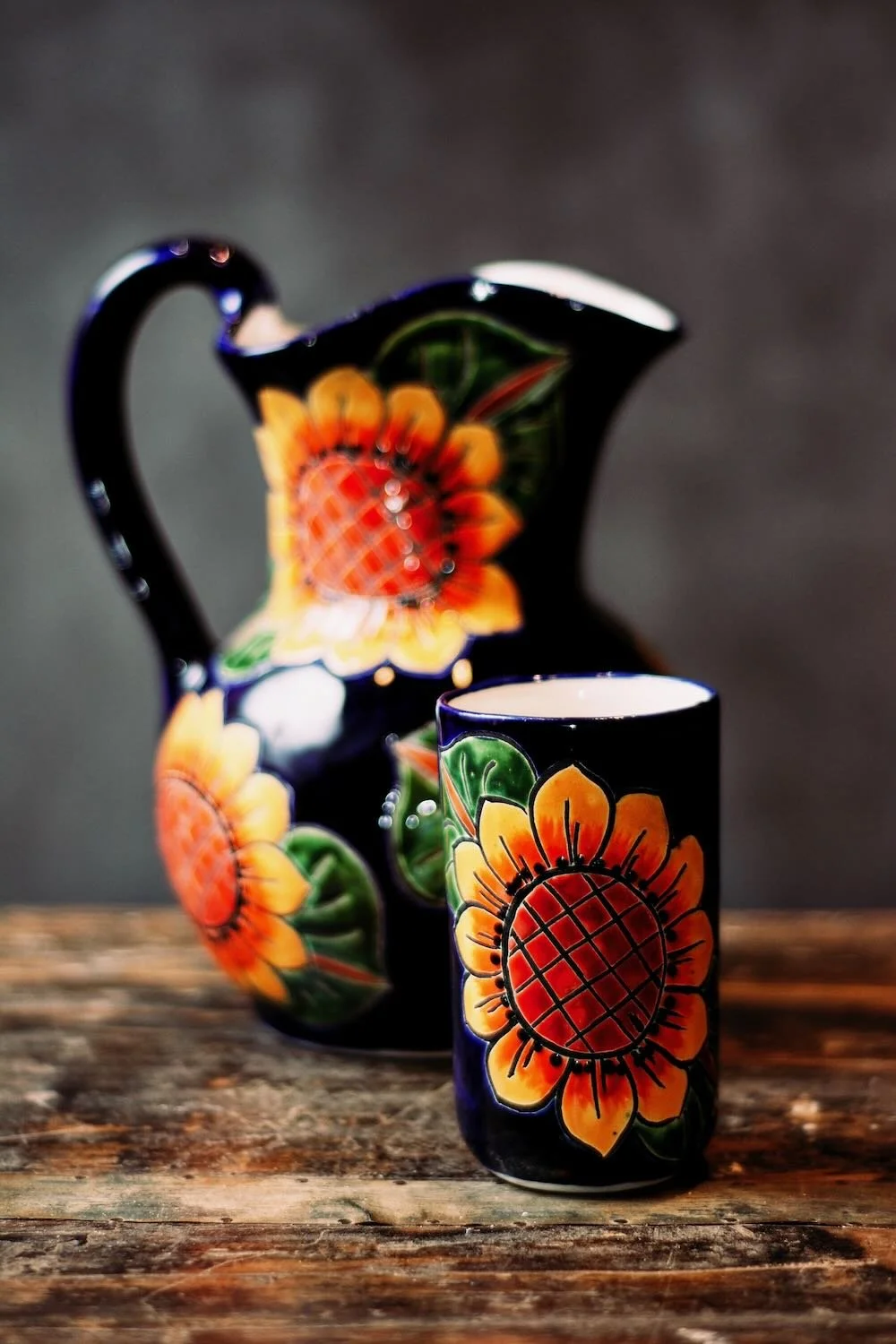 Talavera Sunflower Pitcher & Cup Set. Hand-painted Talavera set featuring a cobalt blue pitcher and matching cups with a vibrant sunflower design.