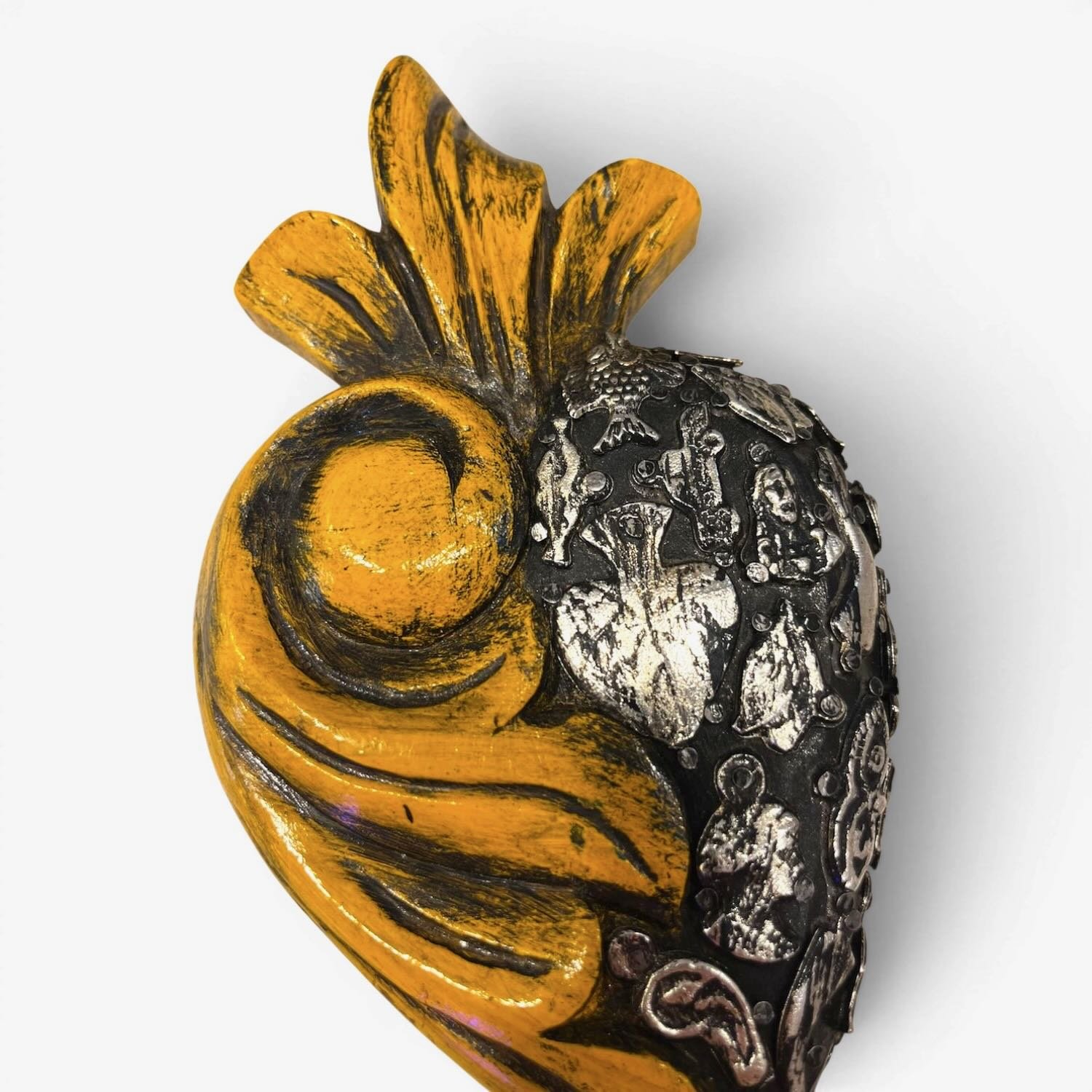Handmade Mexican yellow Milagros heart wall décor with a carved swirl design and traditional silver milagros charms.