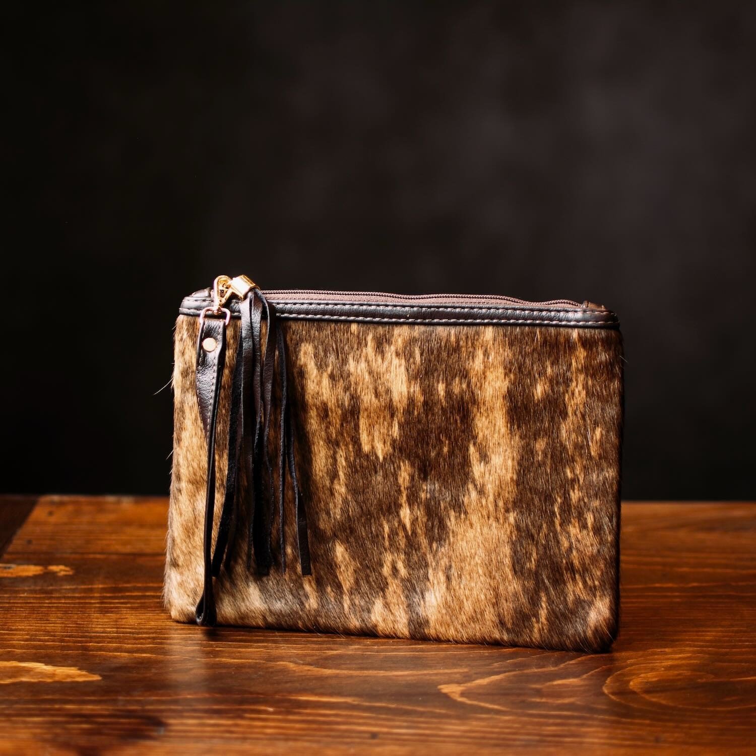 Handmade Brazilian cowhide clutch with fringe detailing, zipper closure, and wrist strap