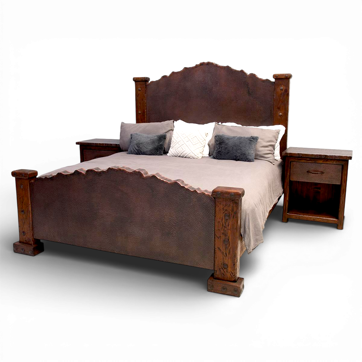 A wooden bed with a high headboard and footboard, topped with a beige bedspread and four decorative pillows, each in shades of gray and white. Two matching wooden nightstands with drawers are on either side of the bed.