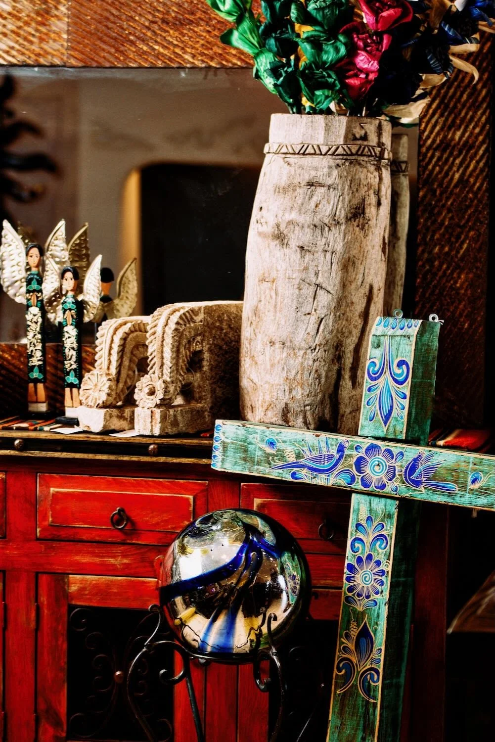 Rich red handmade buffet, turquoise cross, handblown sphere and various decor from Mexico.