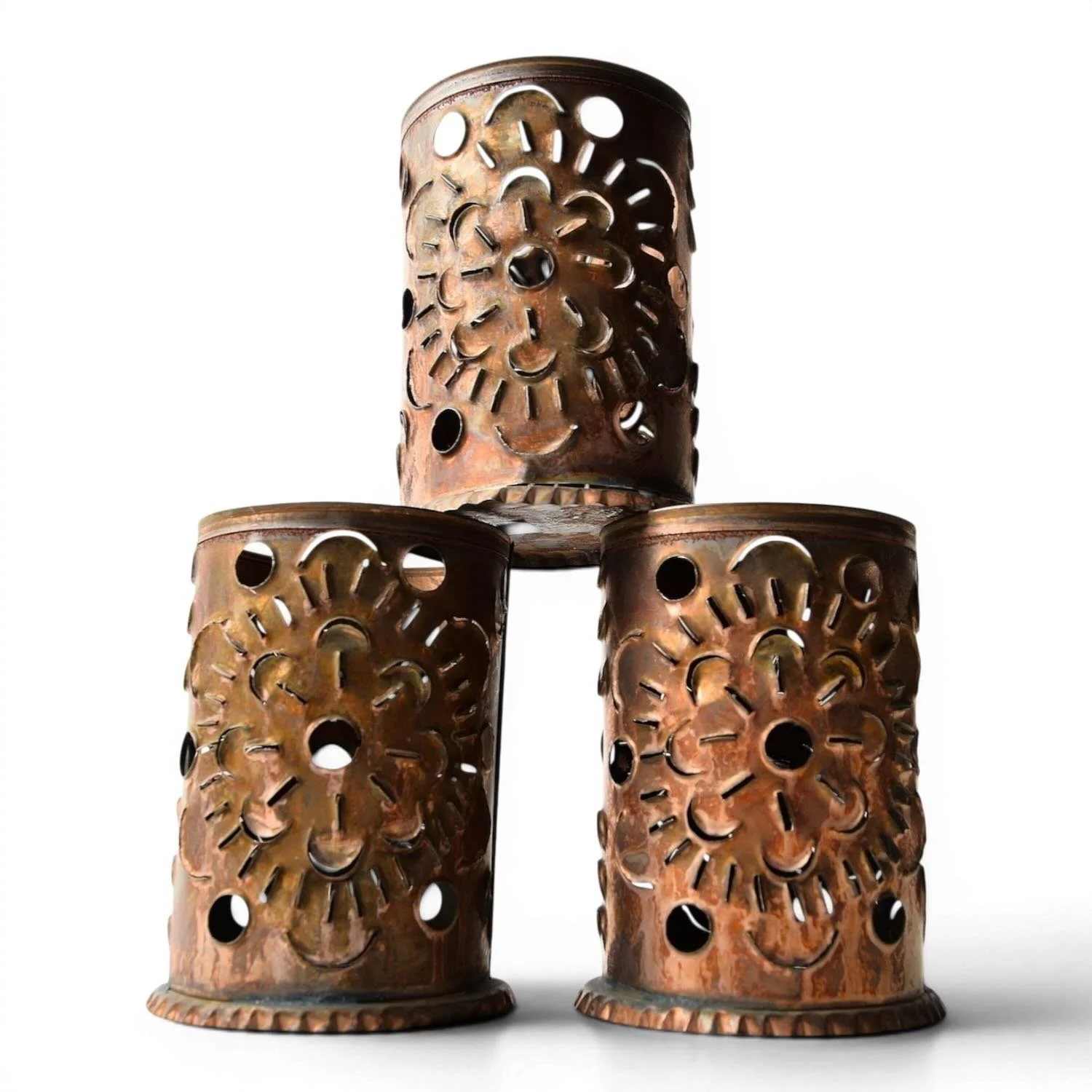 Handmade Luminarias de Bronce candle lanterns in multiple sizes with punched tin bronze finish casting warm ambient light.