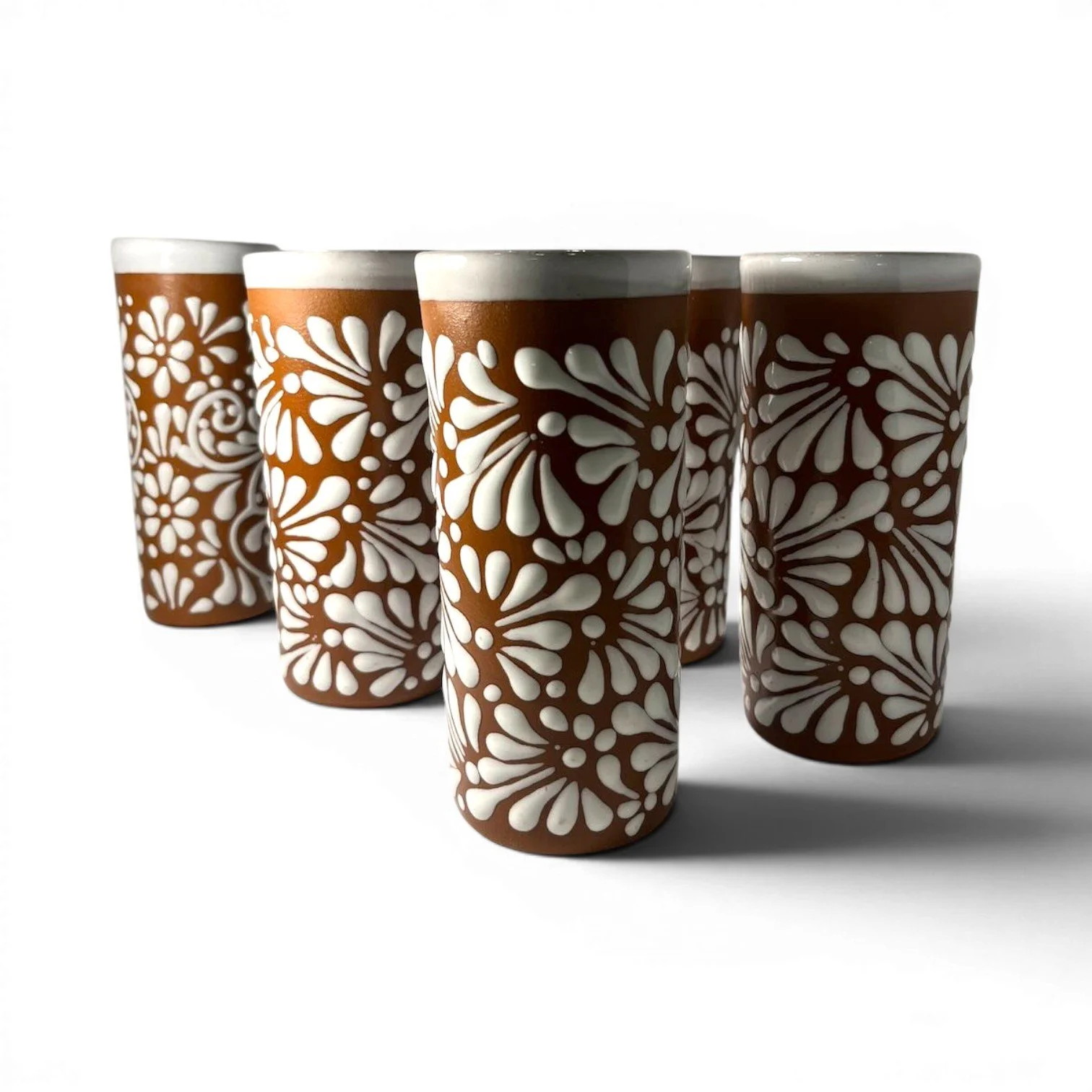 Set of six handmade Mexican Vidrio Terracota tall glasses with textured white floral Talavera-inspired design.