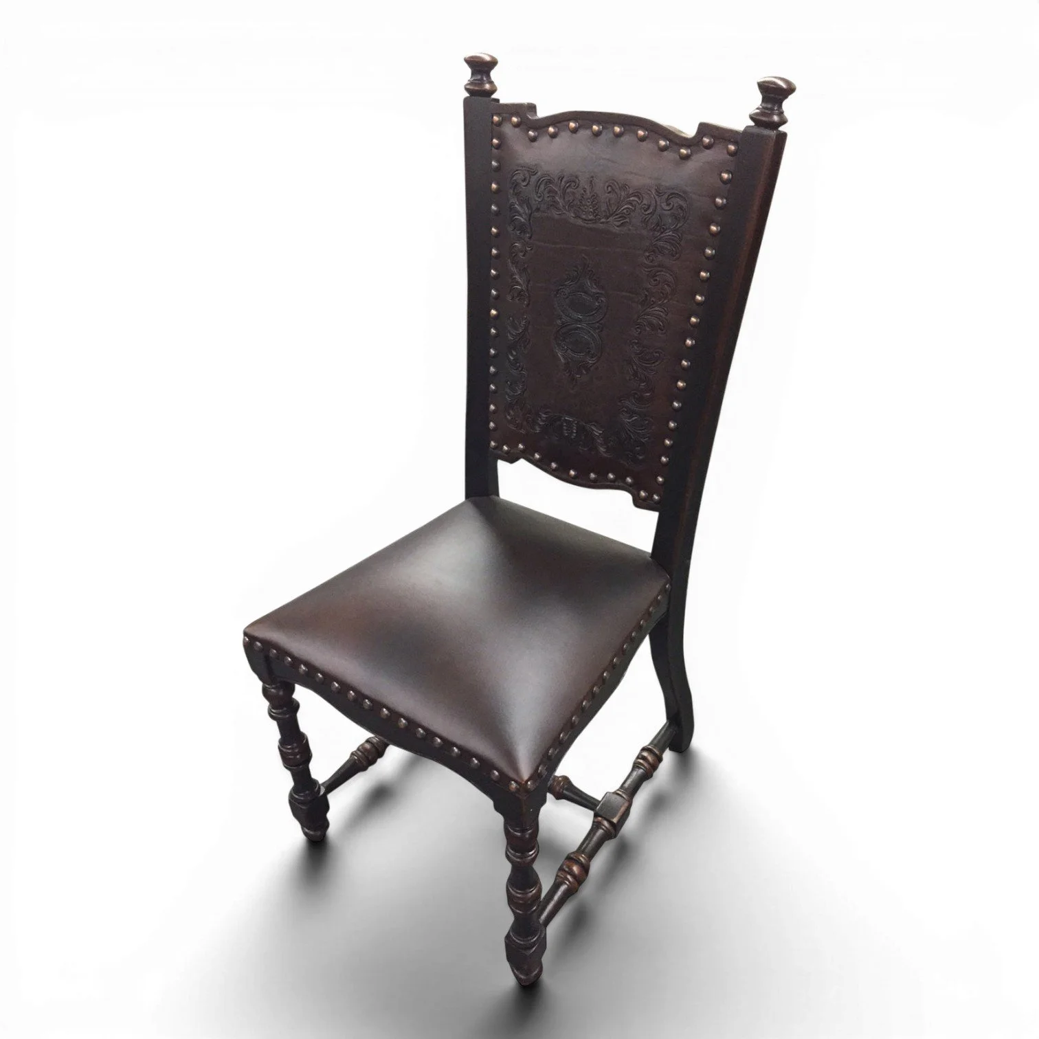 Handmade leather dining chair with tooled leather back, carved wood frame, and nailhead trim