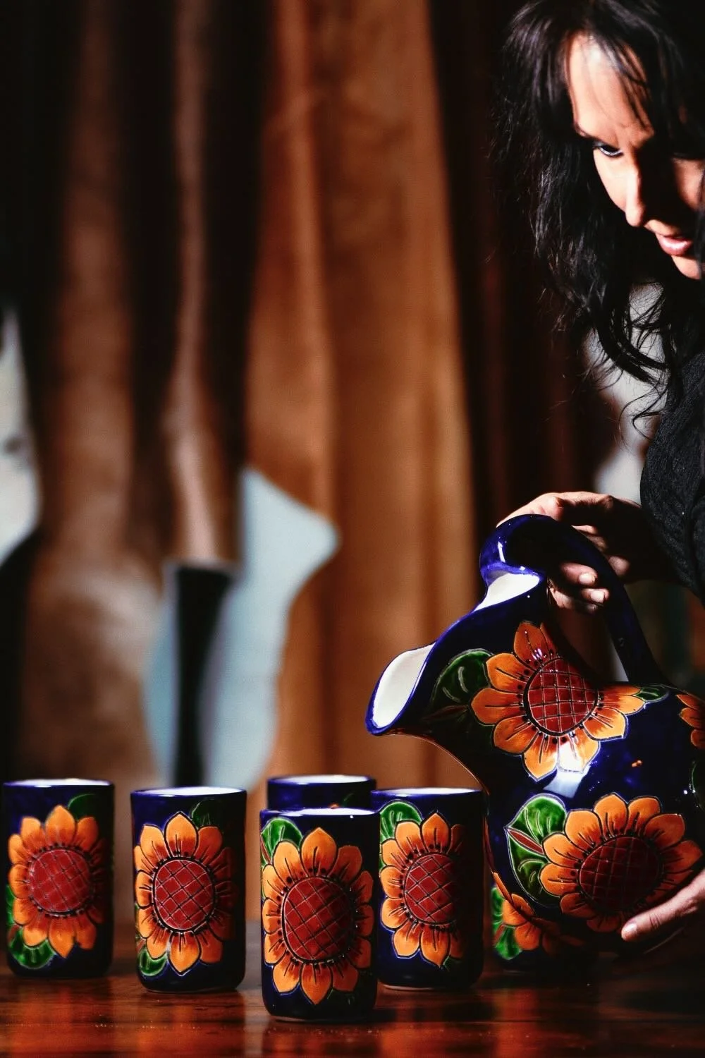 Pretty girl pouring water into a Talavera pitcher and drinking cup set.