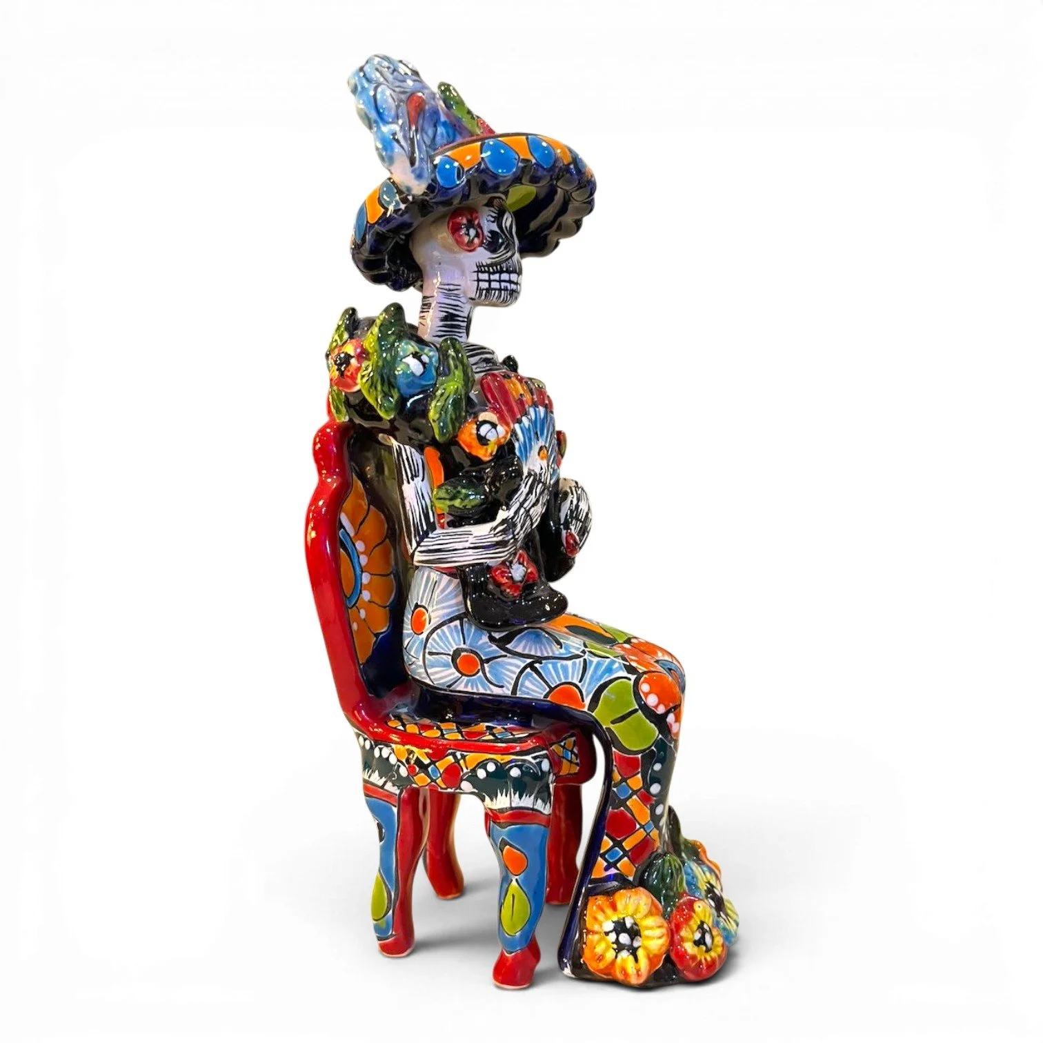 Handmade Mexican Catrina folk art figure seated in a chair holding a fan