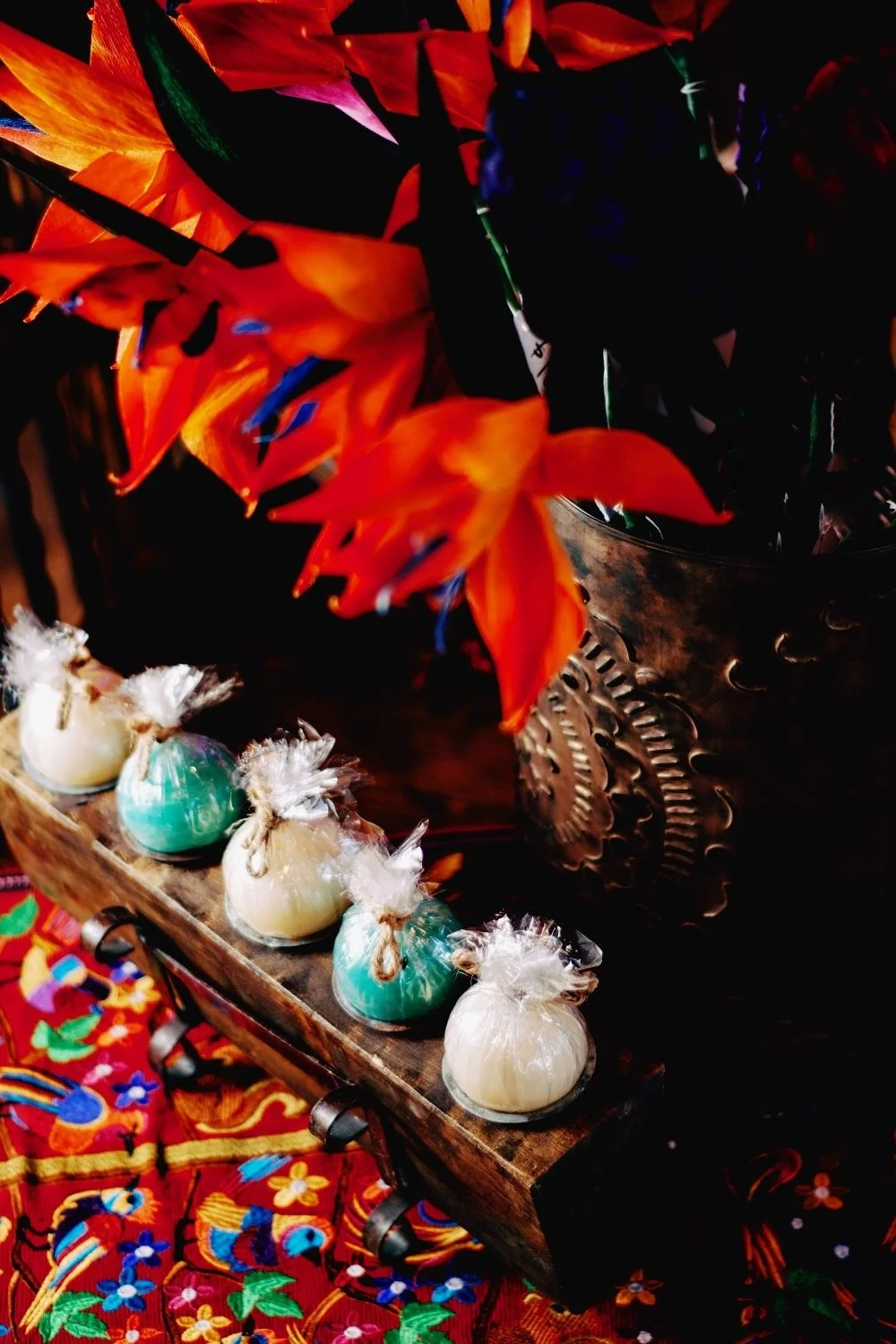 Rustic sugar mold with turquoise and cream candles, embroidered table runner, bronze luminaria with cornhusk calla lilies. All handmade creations from Mexico. Visit Milagros Rústicos in Arizona today.