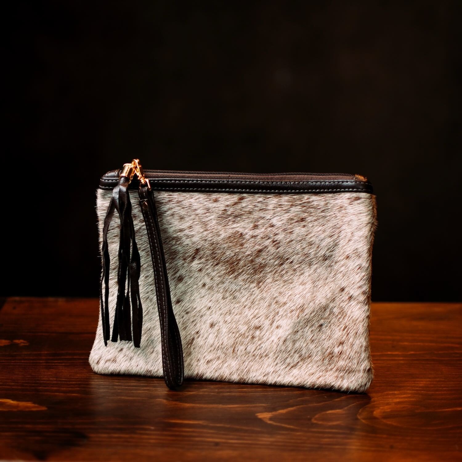 Handmade Brazilian cowhide clutch with fringe detailing, zipper closure, and wrist strap