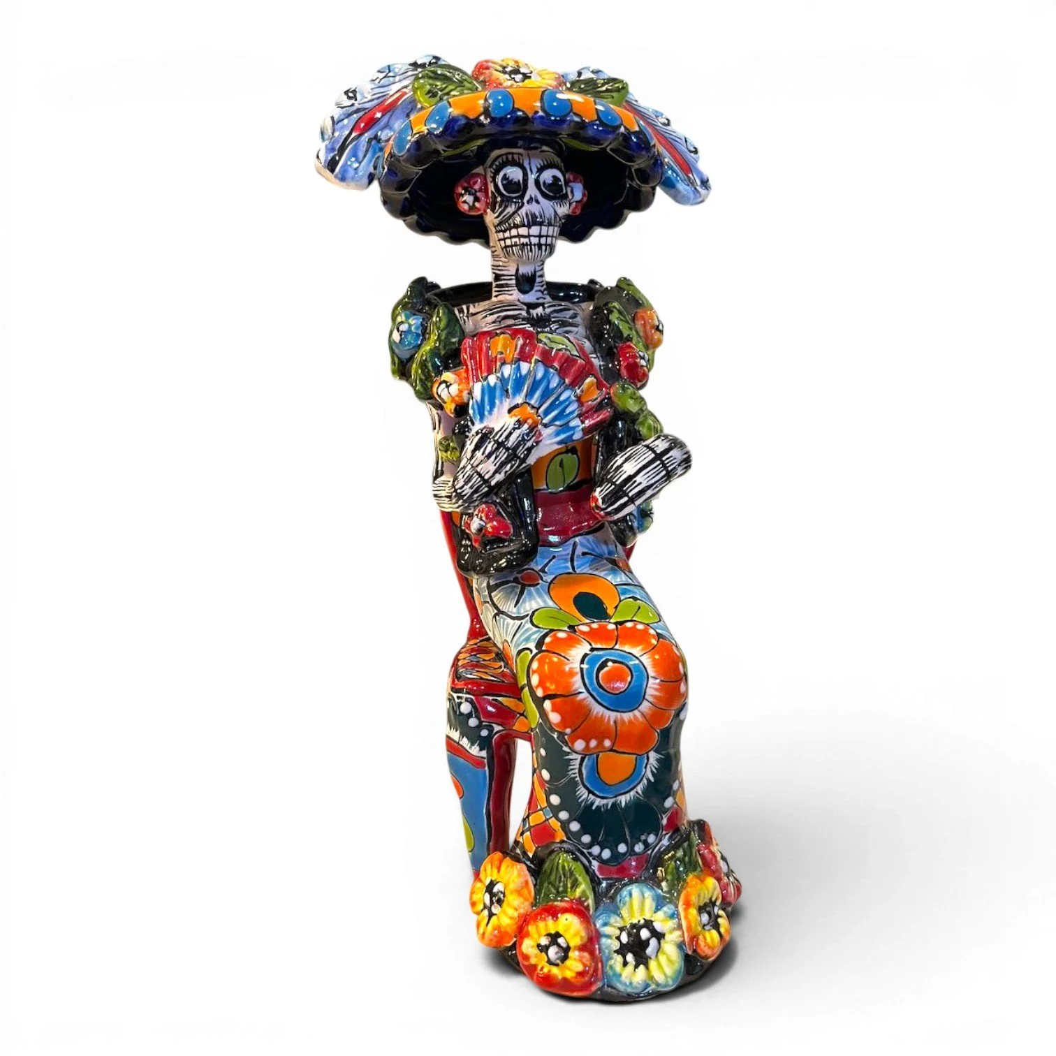 Handmade Mexican Catrina folk art figure seated in a chair holding a fan