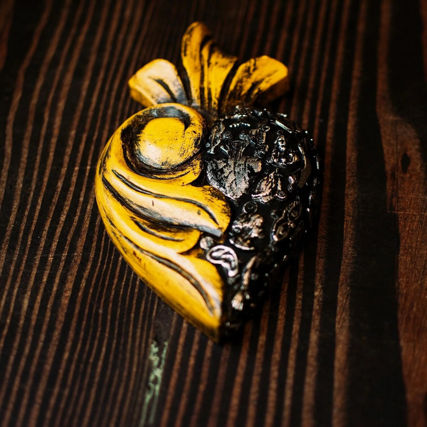 Handmade Mexican yellow Milagros heart wall décor with a carved swirl design and traditional silver milagros charms.