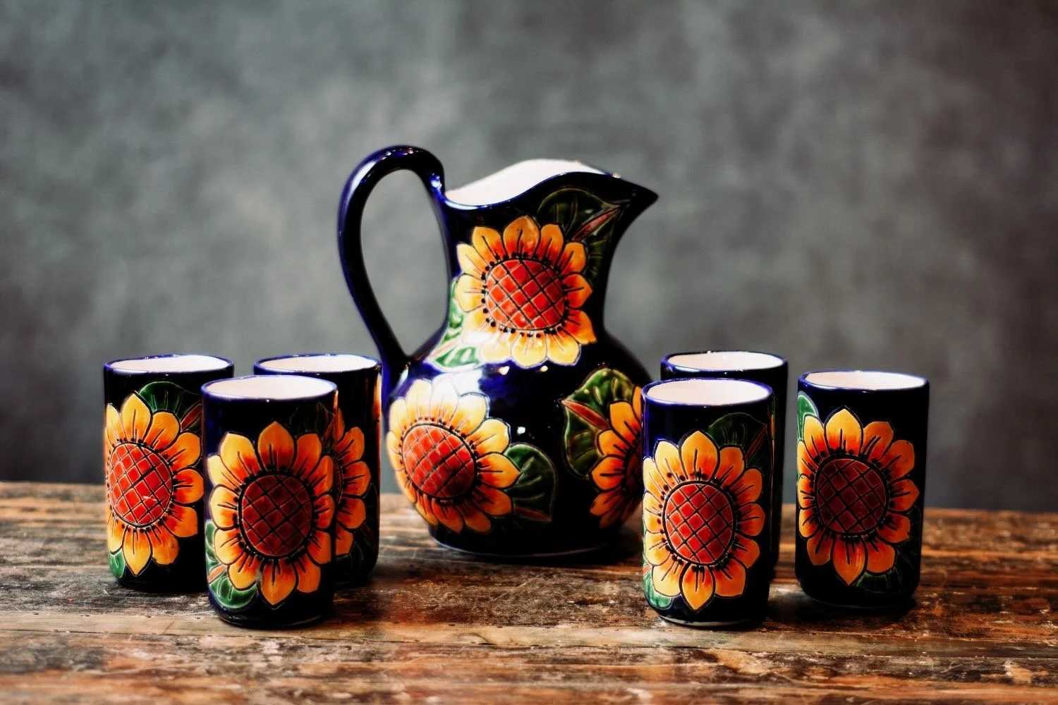 Talavera Sunflower Pitcher & Cup Set. Hand-painted Talavera set featuring a cobalt blue pitcher and matching cups with a vibrant sunflower design.