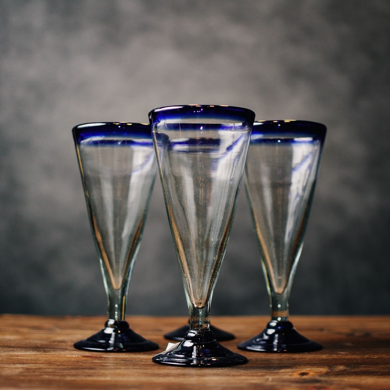 Set of four handmade Mexican handblown pilsner glasses with traditional cobalt blue rims.