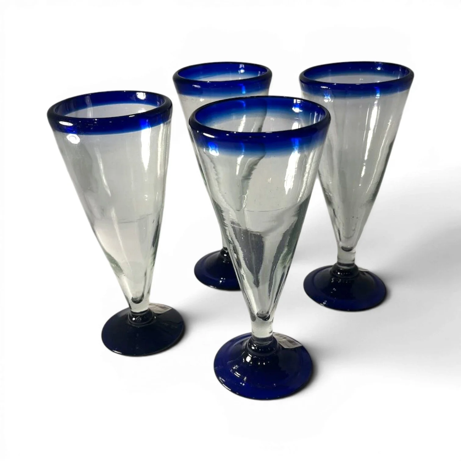 Set of four handmade Mexican handblown pilsner glasses with traditional cobalt blue rims.
