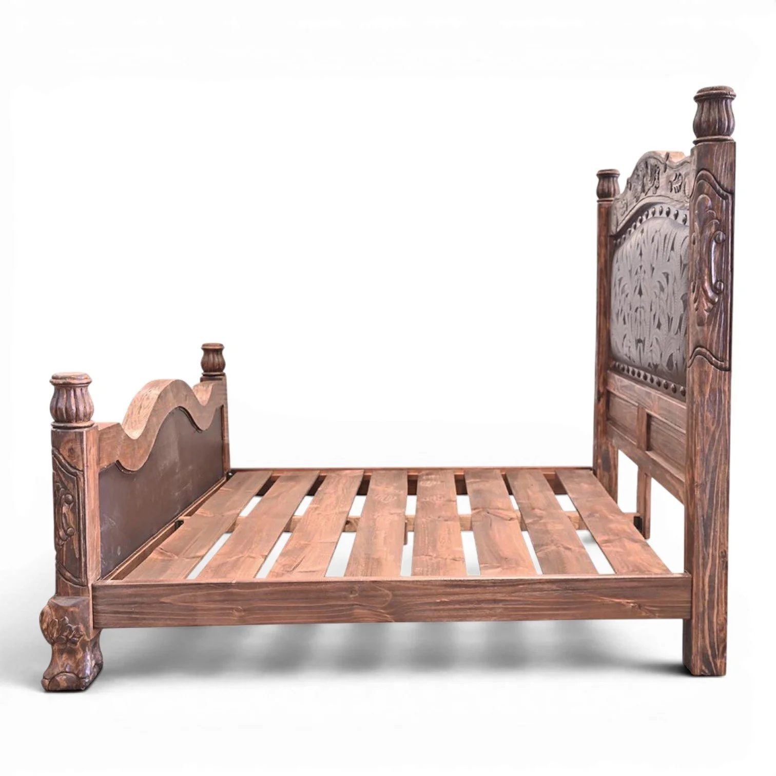 Handmade Red Lodge tooled leather bed with arched headboard, hand-carved wood, iron trim, and decorative clavos.