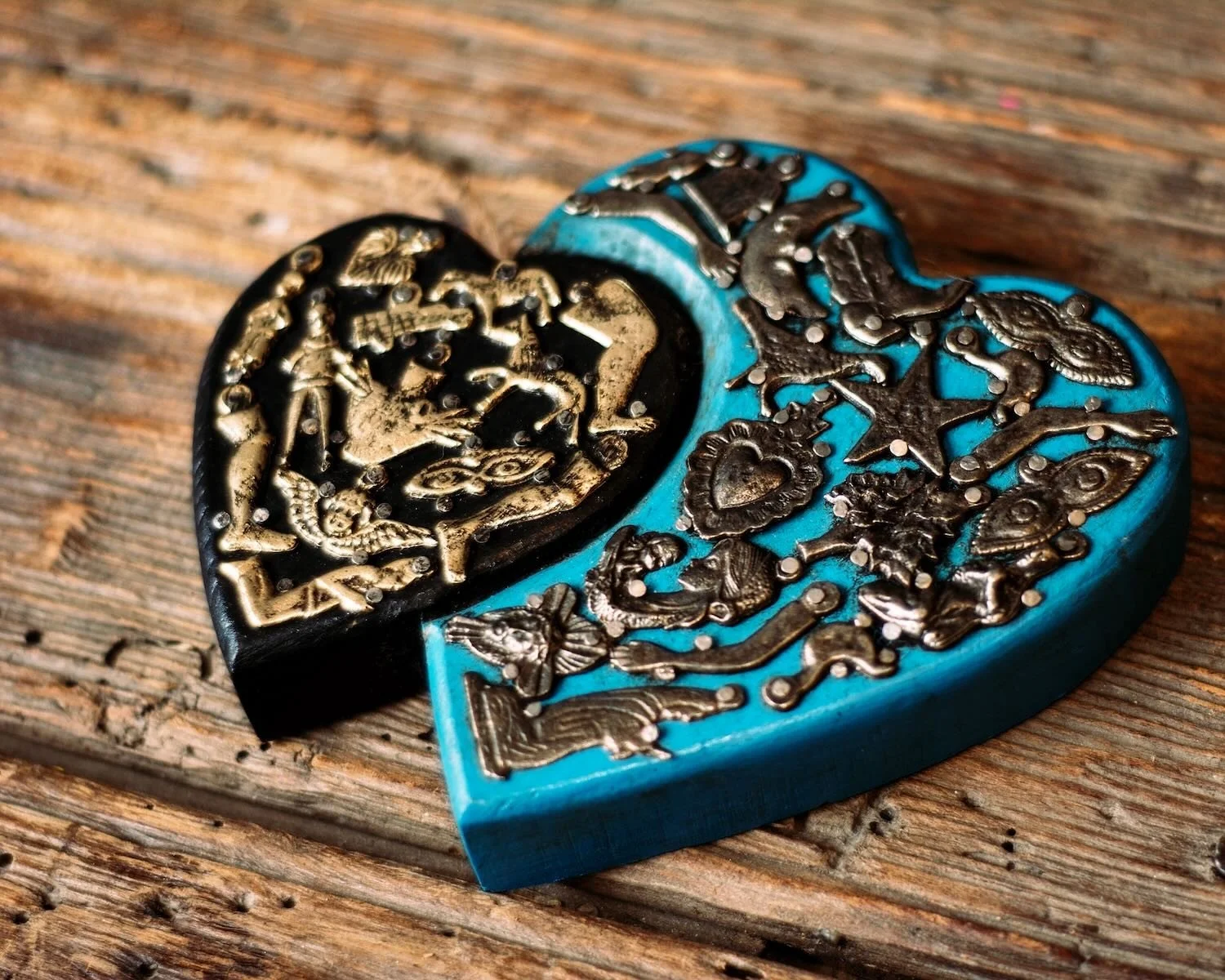 Handmade Mexican double heart wall décor with blue and black hand-painted hearts accented by traditional silver Milagros charms.