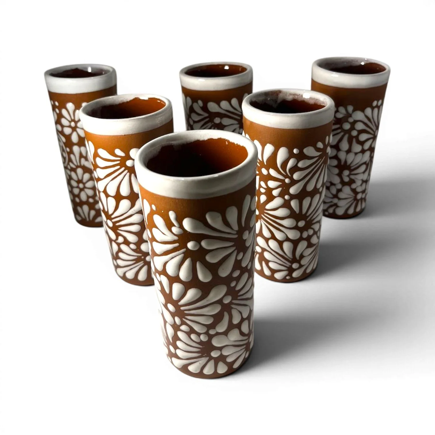 Set of six handmade Mexican Vidrio Terracota tall glasses with textured white floral Talavera-inspired design.