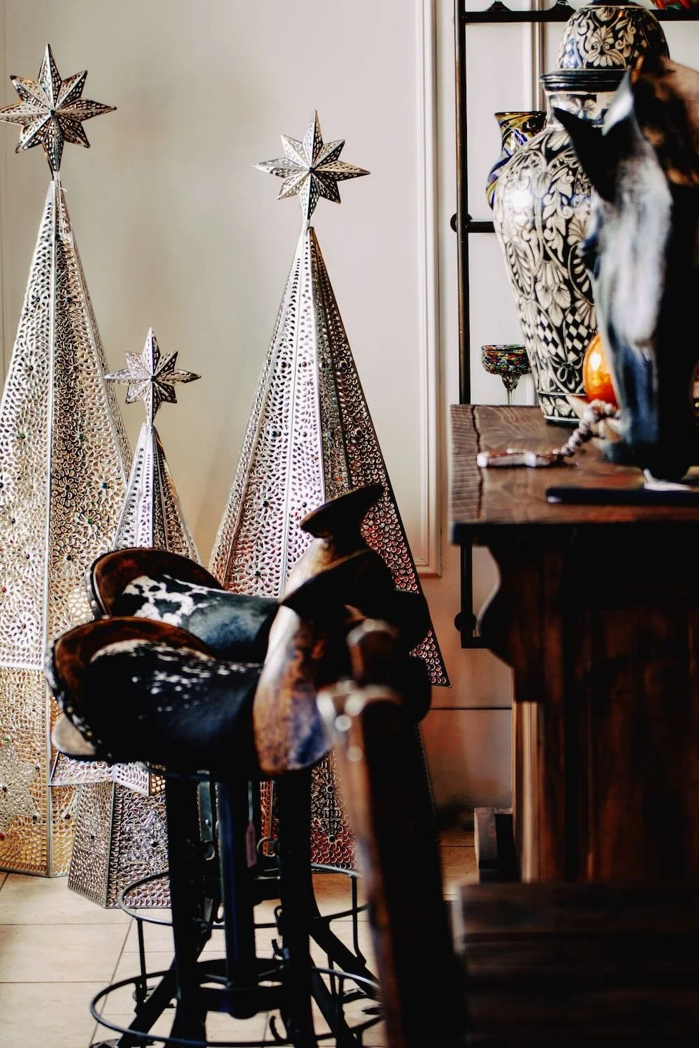 Handmade silver tin lighted Christmas trees, cowhide saddle bar stools and more unique home decor from Mexico. All on the showroom floor at Milagros Rústicos in Arizona.