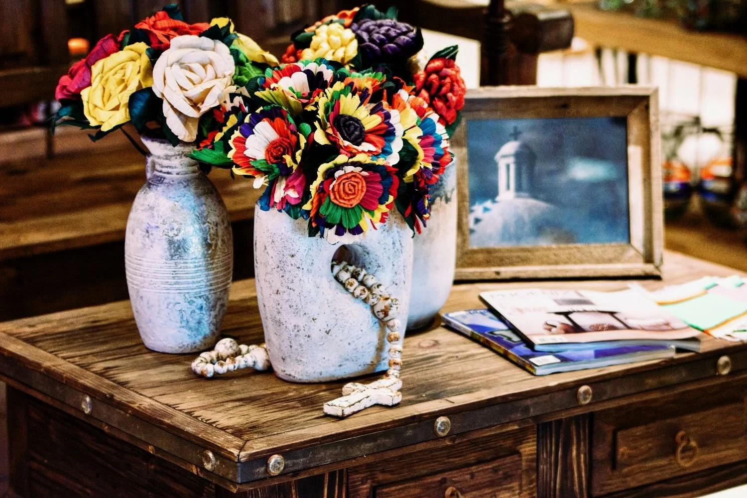 Handmade distressed white pottery, colorful cornhusk flowers on a rustic coffee table from Mexico.