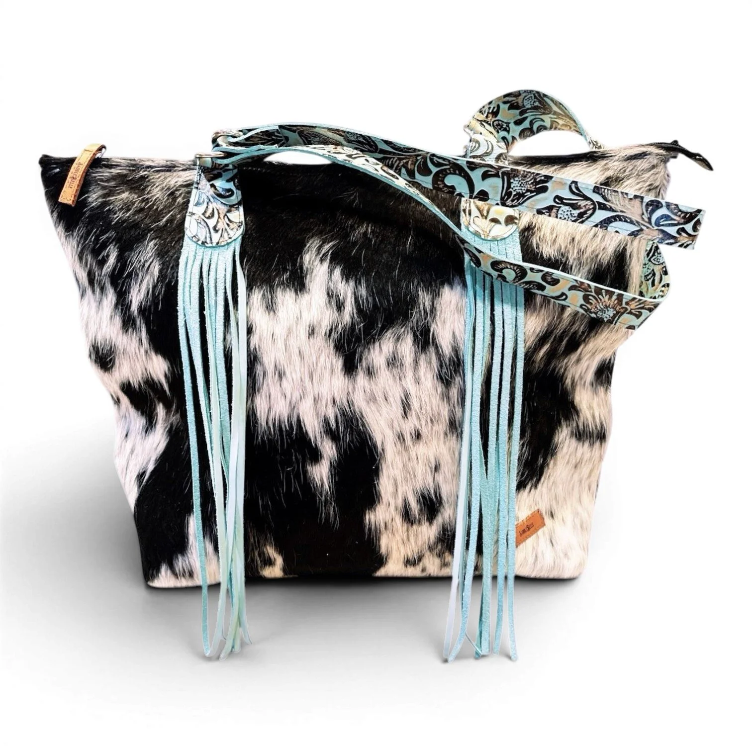 Handmade Brazilian Sheridan cowhide tote bag with black and white cowhide, black leather back, and turquoise fringe