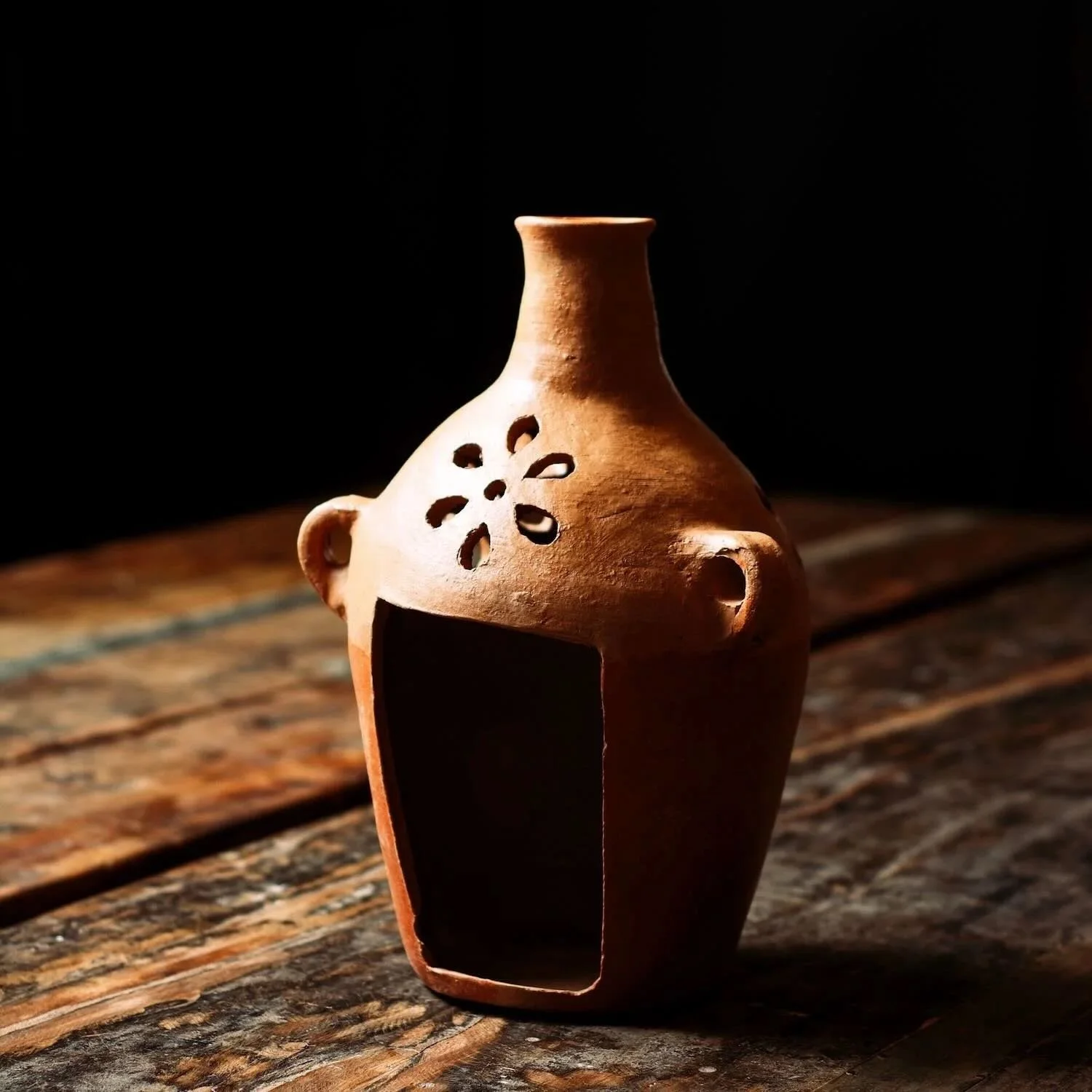 Shop a handmade terracotta jarra luminaria from Oaxaca, Mexico. Clay candle vase with cutouts for warm ambient lighting and rustic decor.