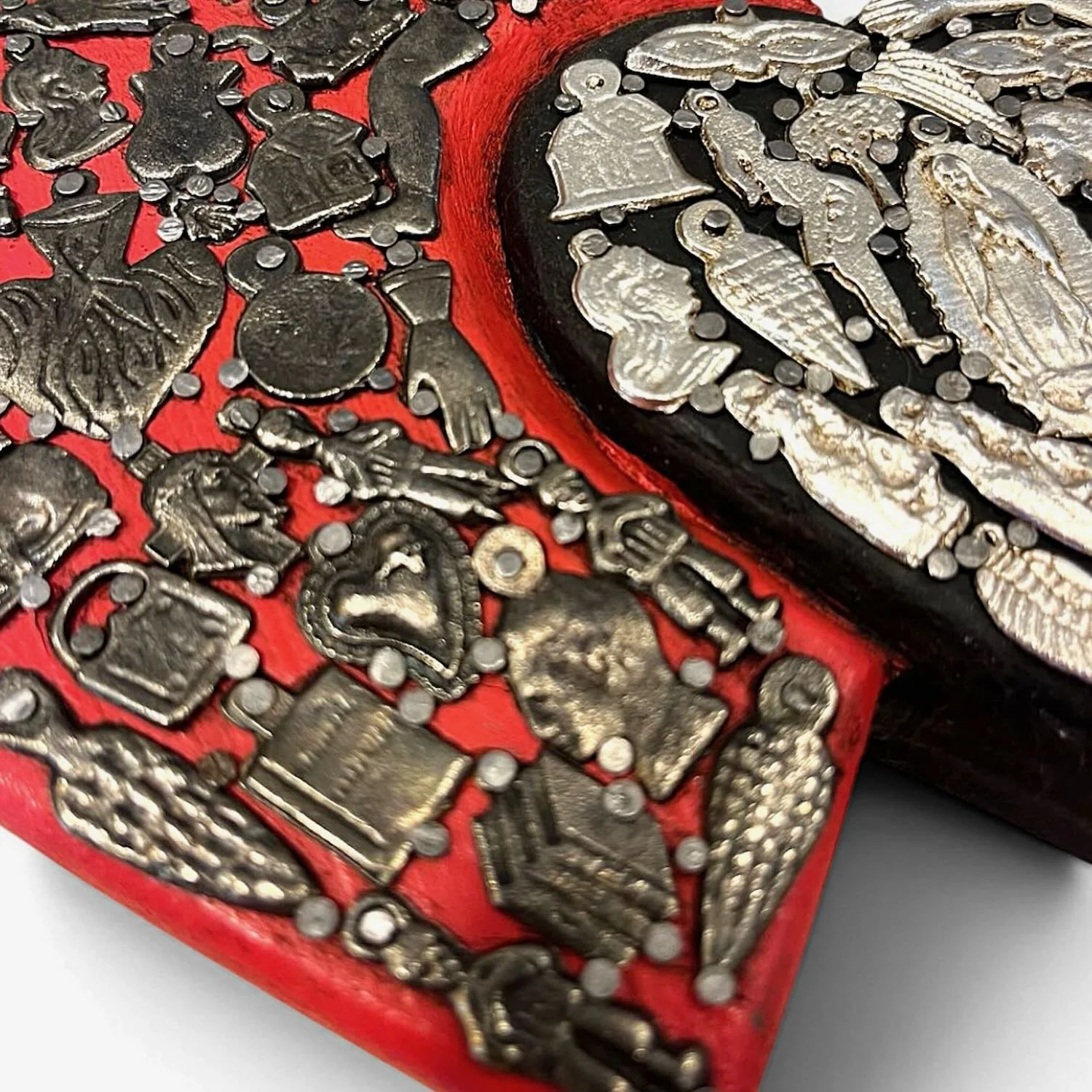 Handmade Mexican double heart wall décor with red and black hand-painted hearts accented by traditional silver Milagros charms.