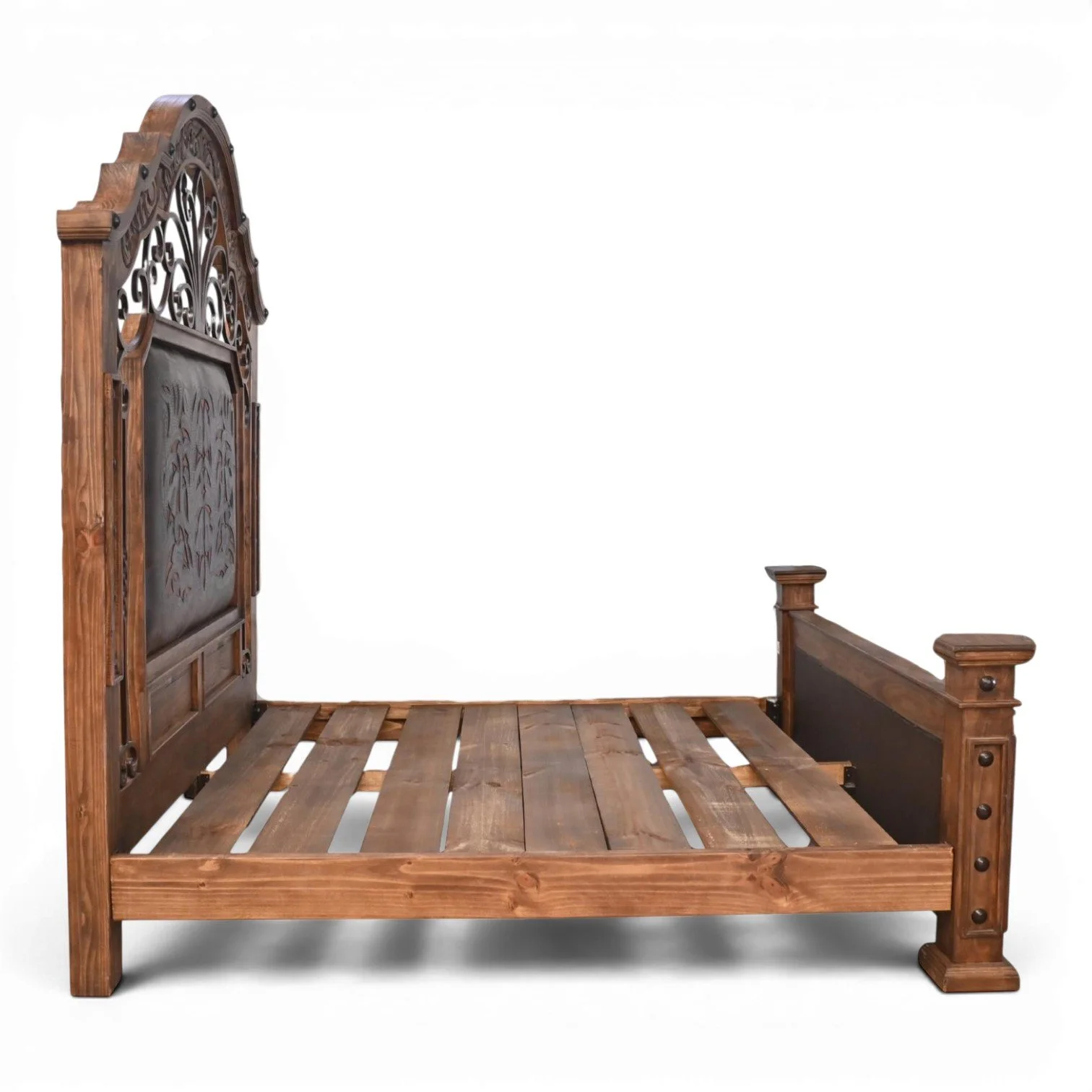 Handmade Hacienda Hierro tooled leather bed with arched headboard, decorative ironwork, hand-carved wood, and rustic clavos accents.