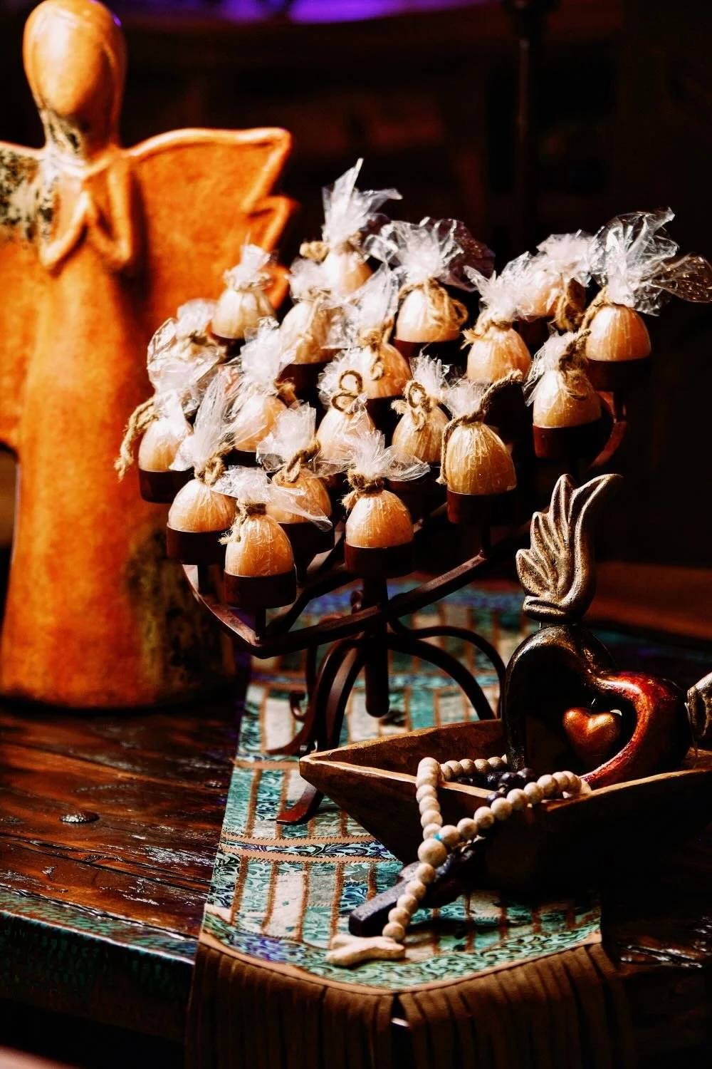 Iron heart shaped candelabra from Mexico on a rustic reclaimed wood coffee table and tooled leather and cowhide table runner.