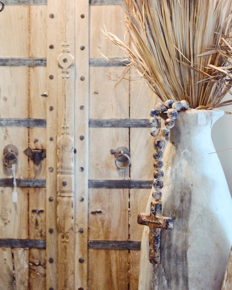 Antique door and distressed white terracotta vase with rosary beads.