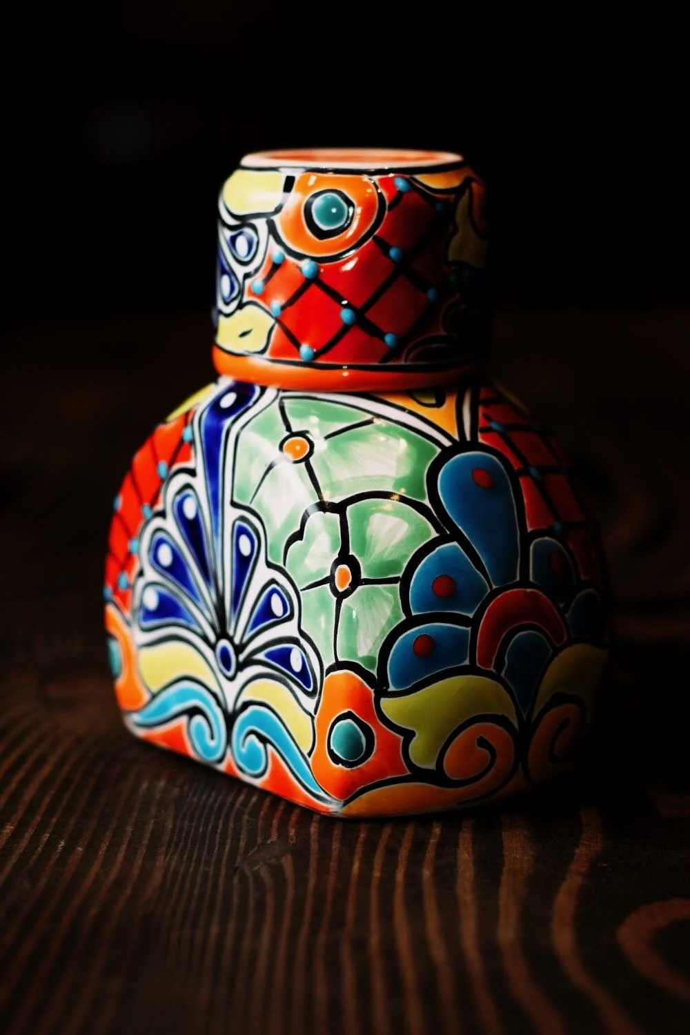 Shop a handmade Talavera tequila bottle with cup lid from Mexico. Colorful, lead-free artisan barware perfect for serving and display.