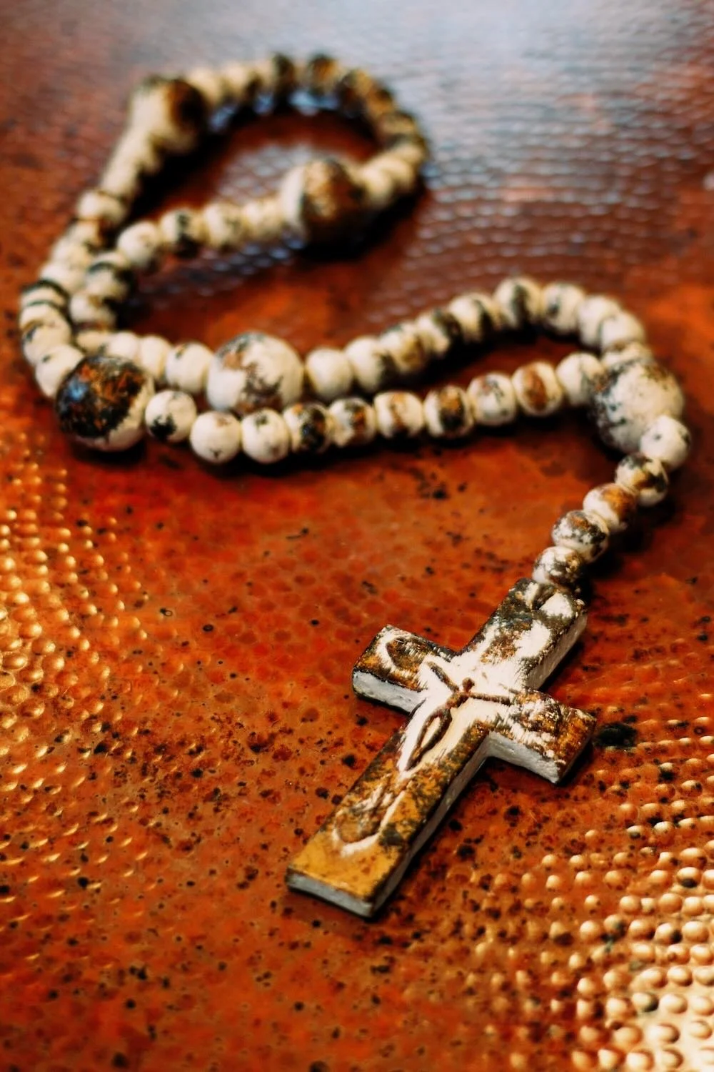 Rosario de Barro. Handcrafted 27" clay rosary from Milagros Rústicos. Features a distressed cream finish. Ideal for home altars or decorative styling.