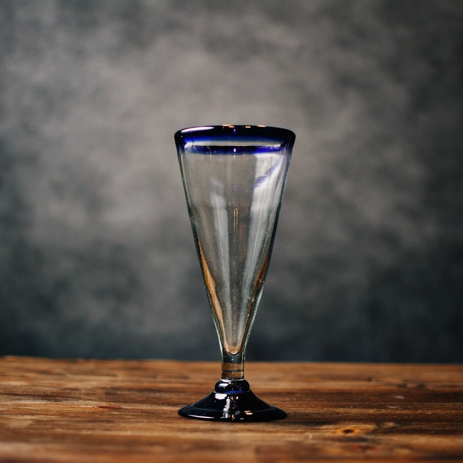 Set of four handmade Mexican handblown pilsner glasses with traditional cobalt blue rims.