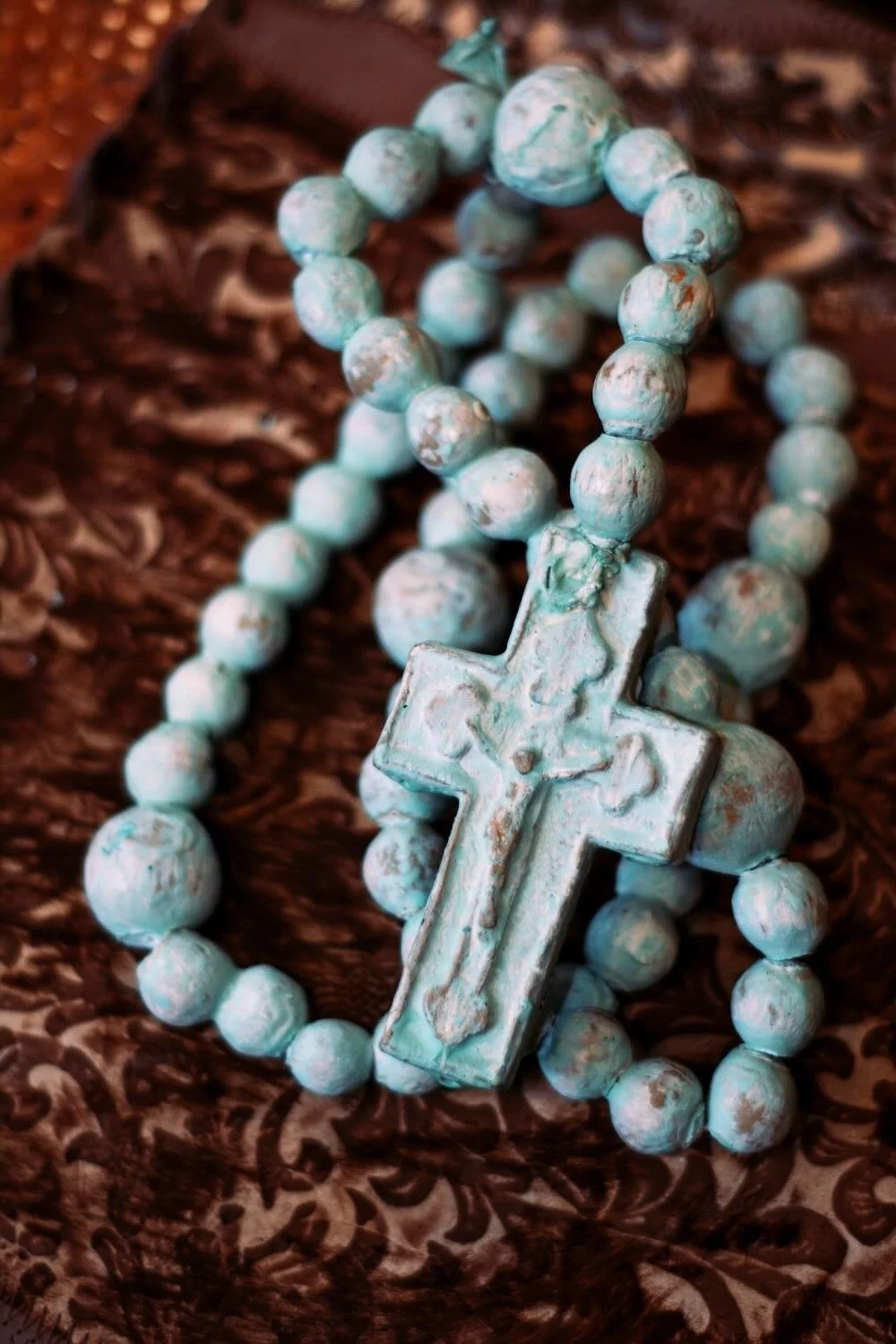 Rosario de Barro - Turquesa. Handcrafted 27" turquoise clay rosary from Milagros Rústicos. Features a distressed finish. Ideal for home altars or rustic decor.