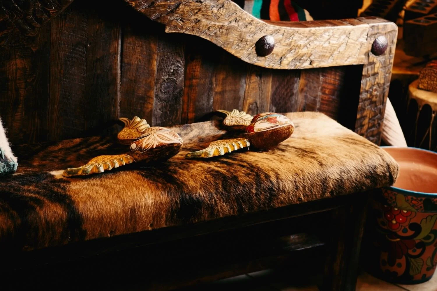 Cowhide bench, rustic bed and clay sacred hearts from Mexico.