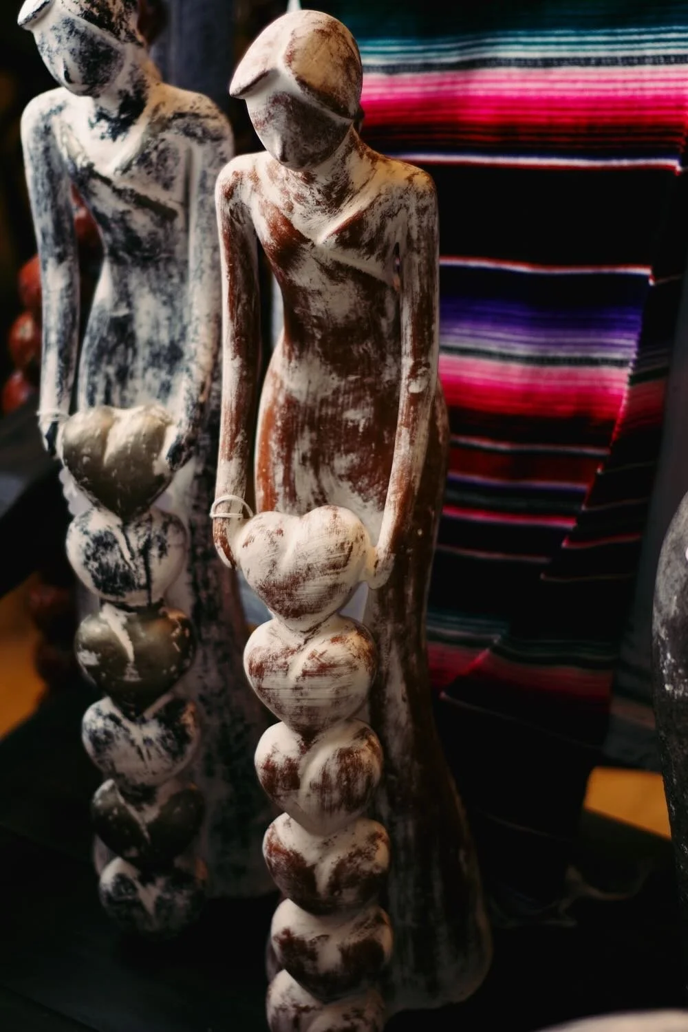 Clay ladies with stacks of hearts on a rustic bench from Mexico.