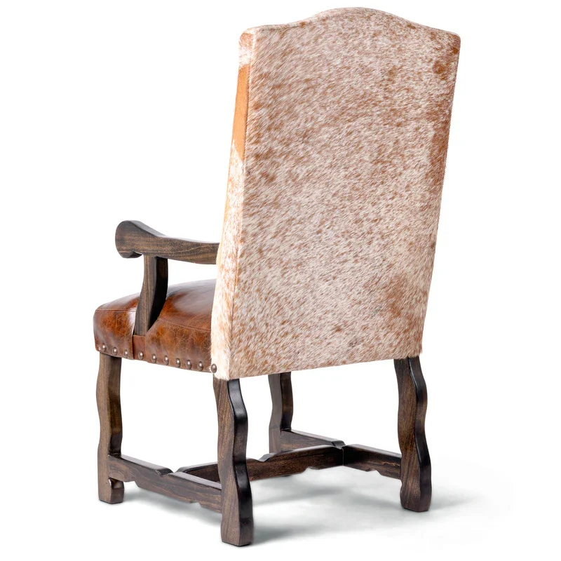 The Boulder Canyon Arm Dining Chair features leather upholstery, a cowhide-wrapped backrest, and solid hardwood construction for bold Western dining style and comfort.