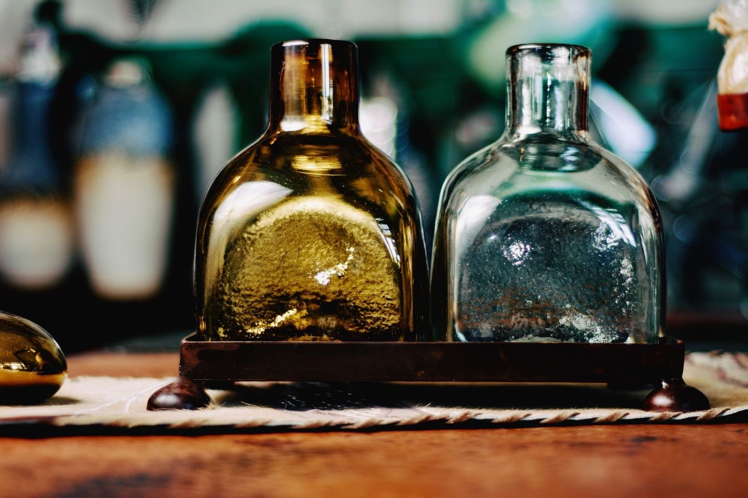 Handmade Mexican serving set featuring two handblown glass bottles and a handcrafted iron tray, perfect for entertaining and rustic décor.