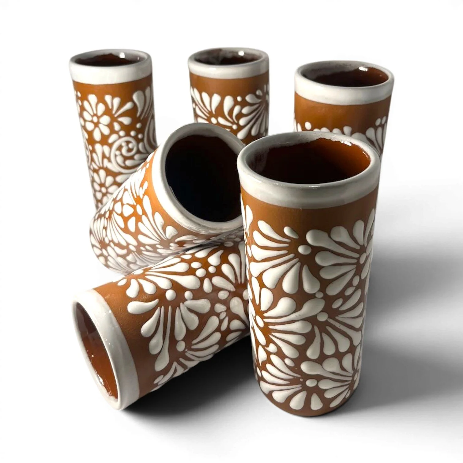 Set of six handmade Mexican Vidrio Terracota tall glasses with textured white floral Talavera-inspired design.
