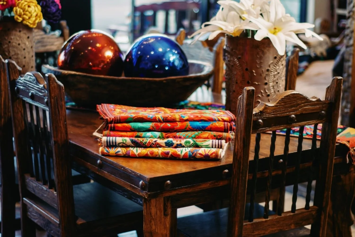 Rustic handmade dining table and chairs with embroidered table runners and hand blown glass balls from Mexico.