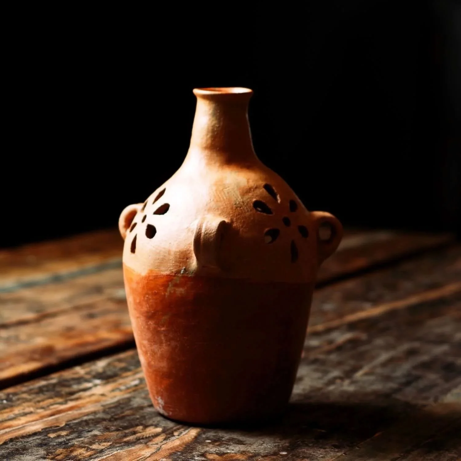 Shop a handmade terracotta jarra luminaria from Oaxaca, Mexico. Clay candle vase with cutouts for warm ambient lighting and rustic decor.
