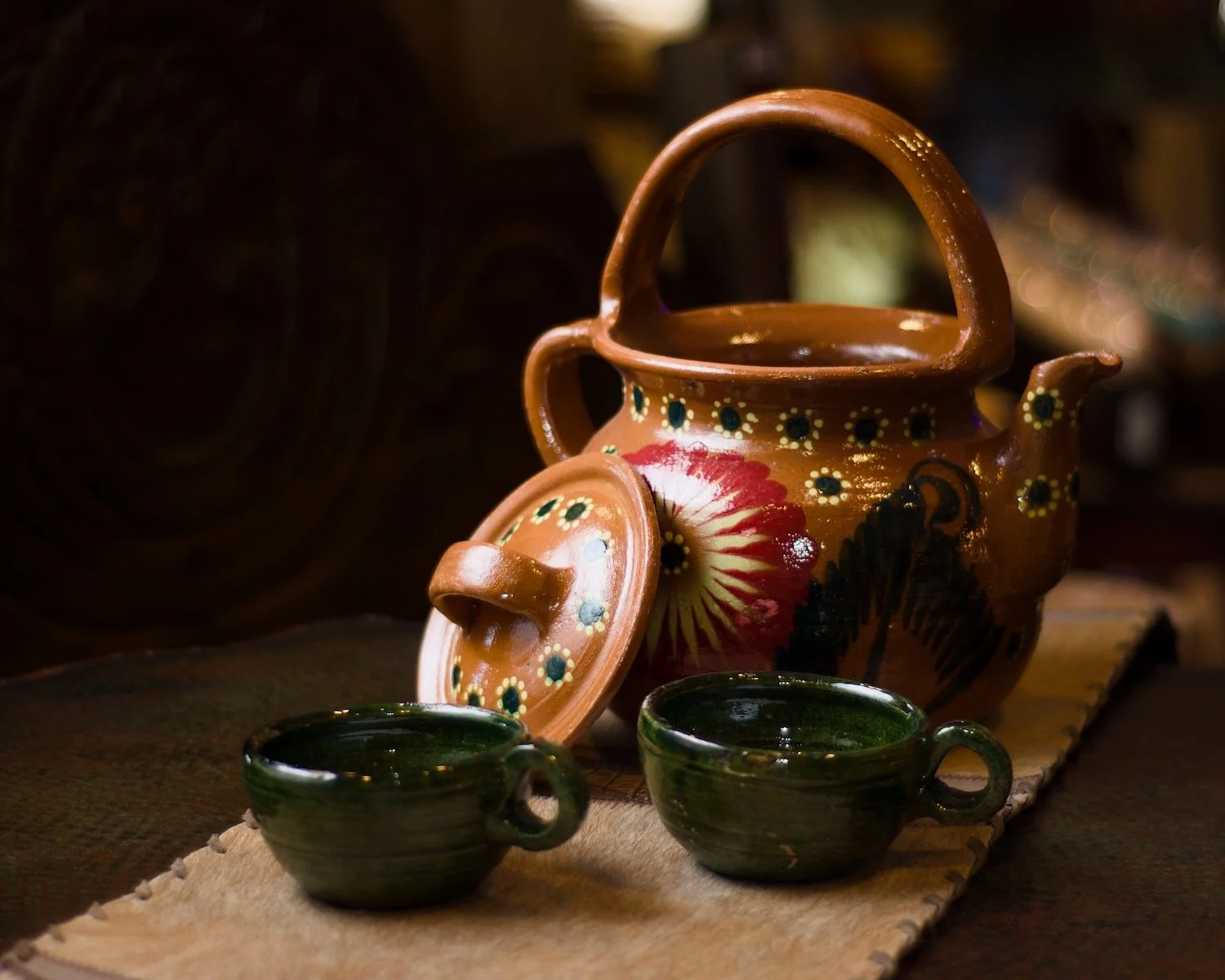 Cafetera de barro con flores y tazas