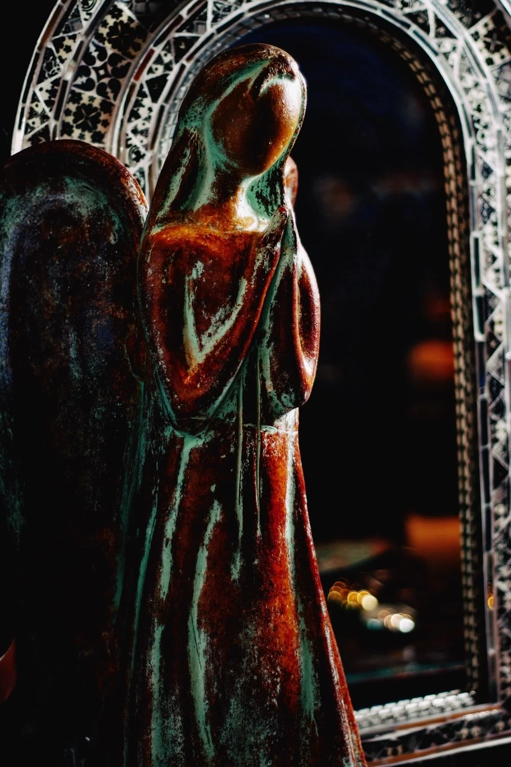 Clay angel praying in front of a black and white Talavera mirror. All handmade in Mexico. Visit Milagros Rústicos in Mesa, Arizona.