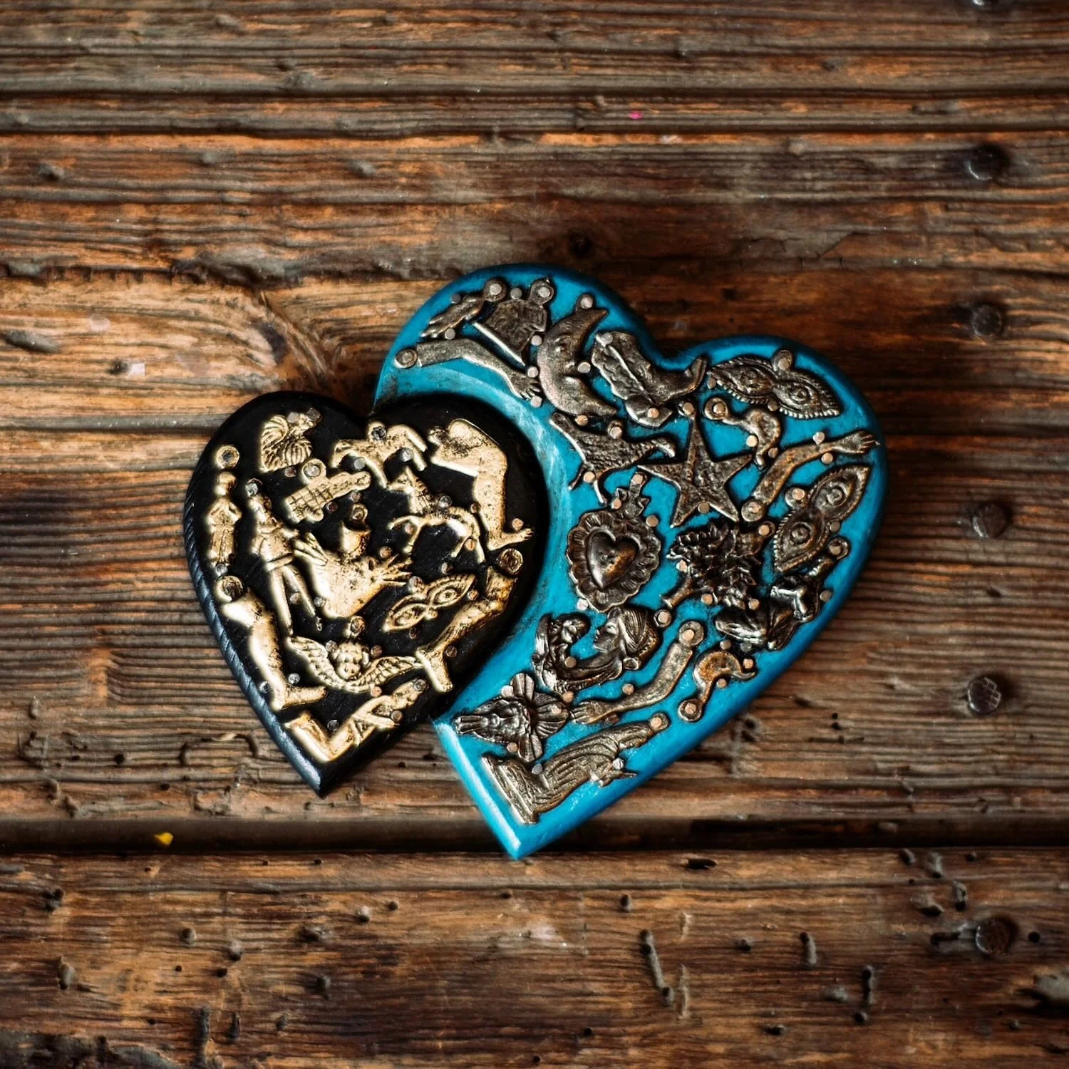 Handmade Mexican double heart wall décor with blue and black hand-painted hearts accented by traditional silver Milagros charms.