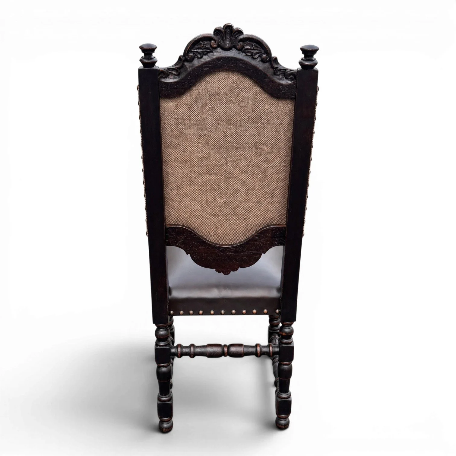 Handmade dining chair with dark carved wood frame, leather seat, and nailhead trim